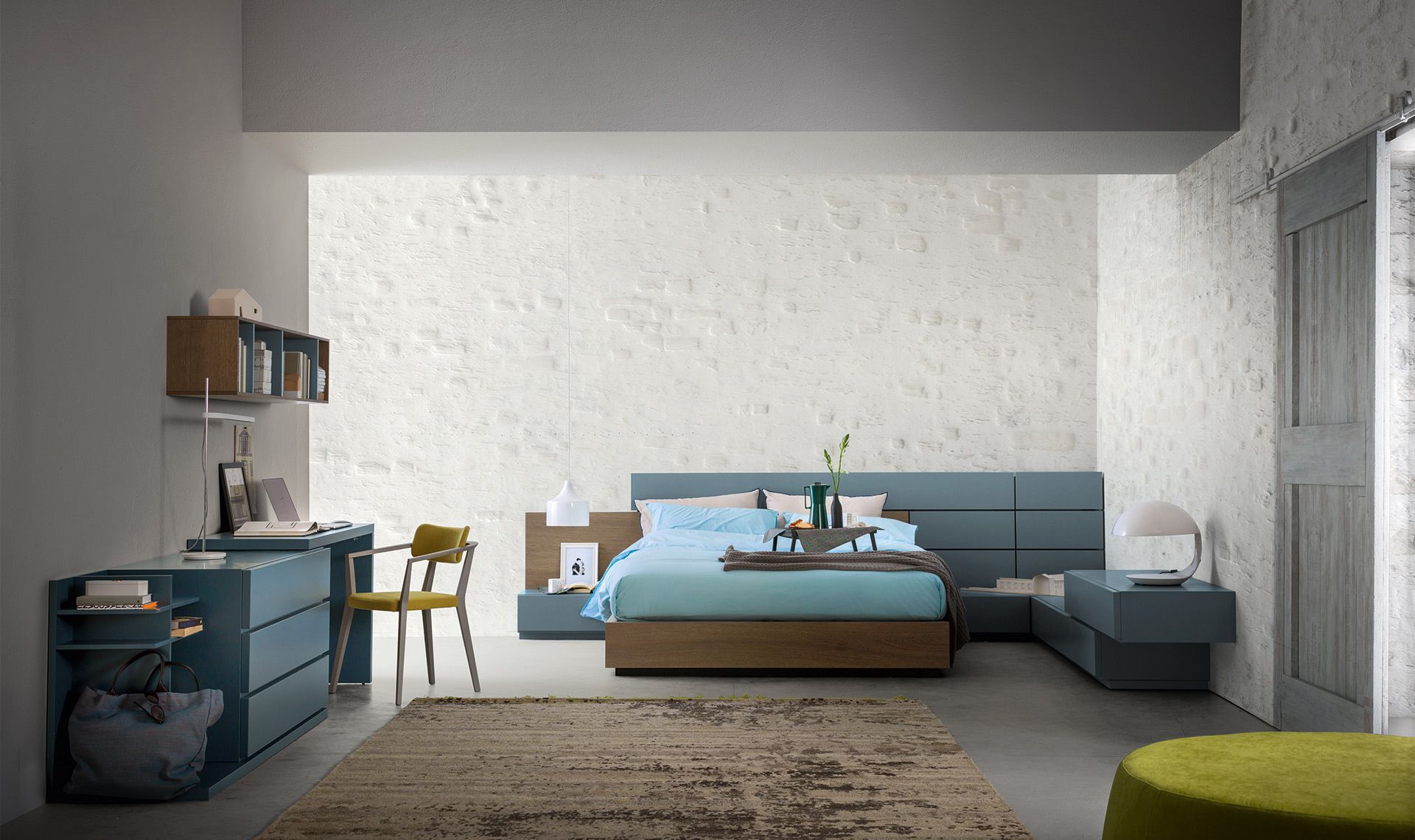 Camera da letto moderna con dettagli blu, scrivania, letto e tappeto decorativo.