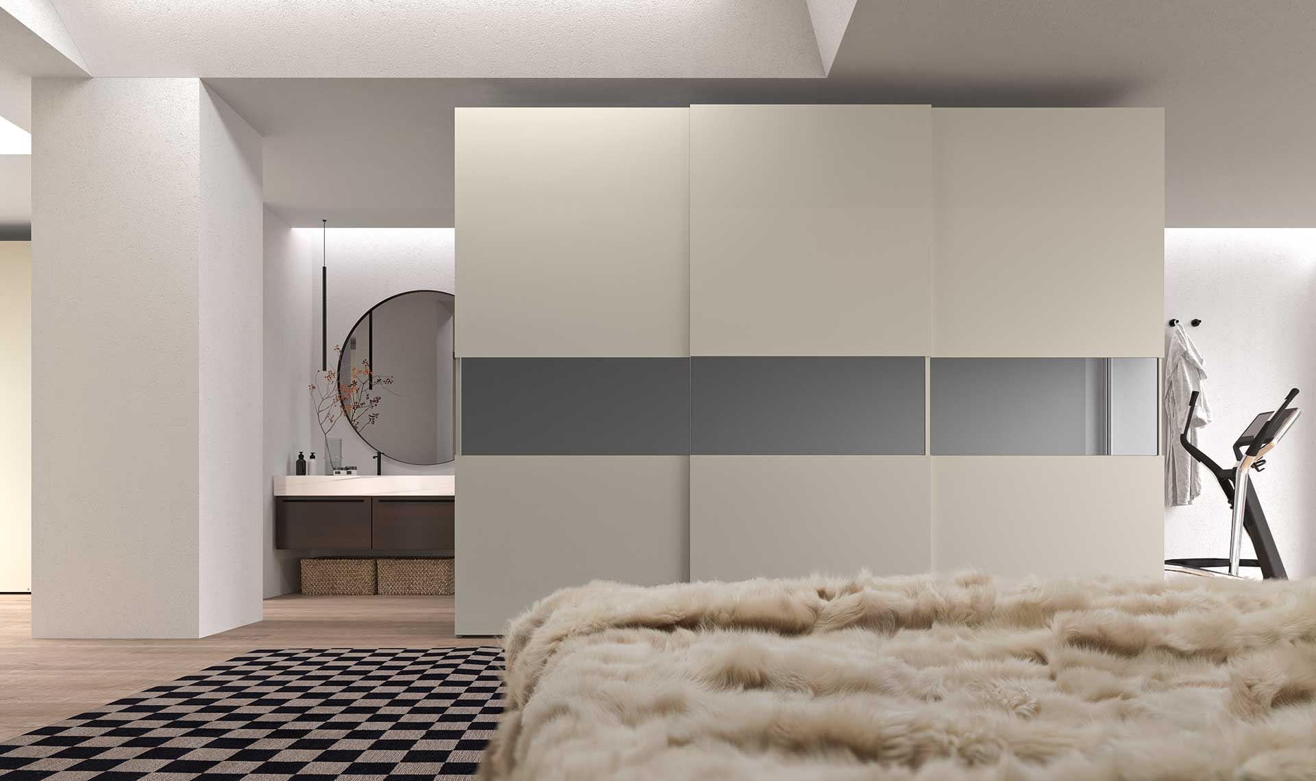 Camera da letto con grande armadio color crema, coperta di pelliccia, tappeto bianco e nero e bagno sullo sfondo.