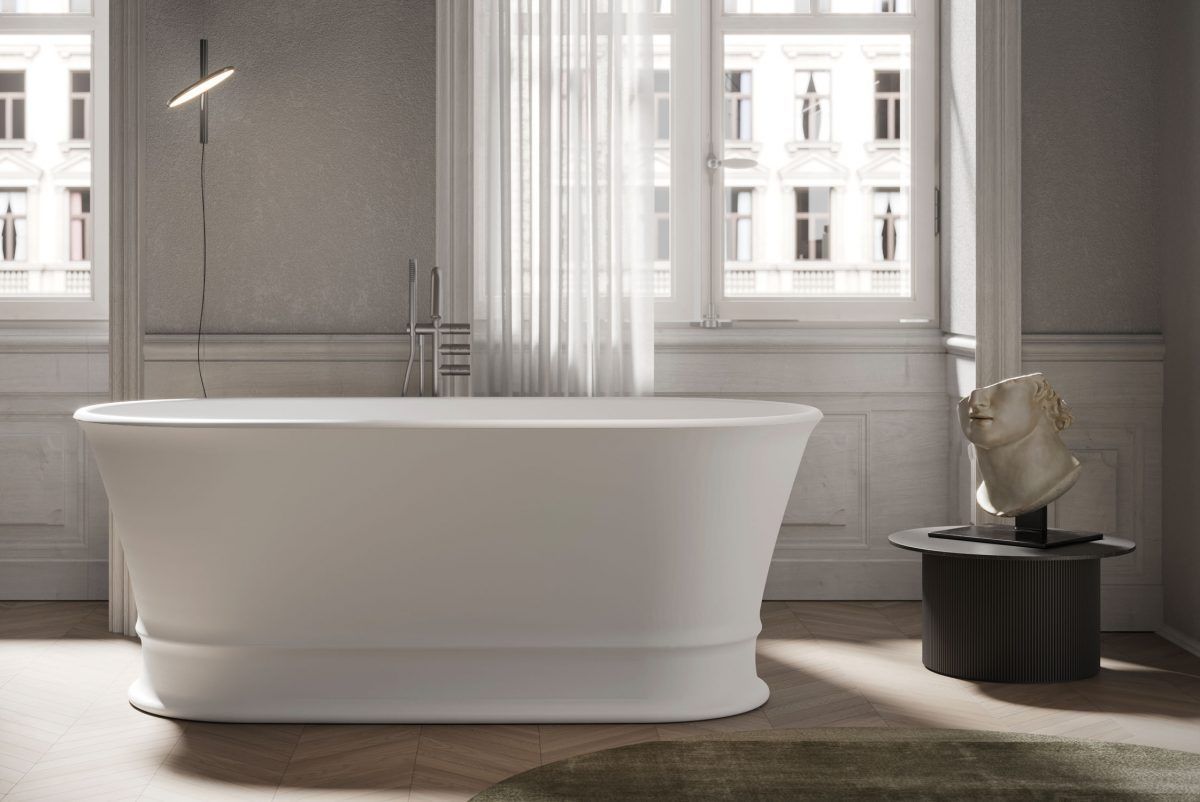 Vasca da bagno bianca in un bagno moderno con luce naturale, un tavolino e una finestra con vista sulla città.