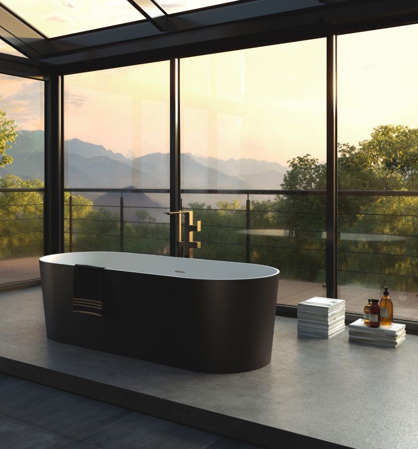 Vasca da bagno nera indipendente in una stanza con pareti in vetro e vista sulle montagne e sul tramonto.