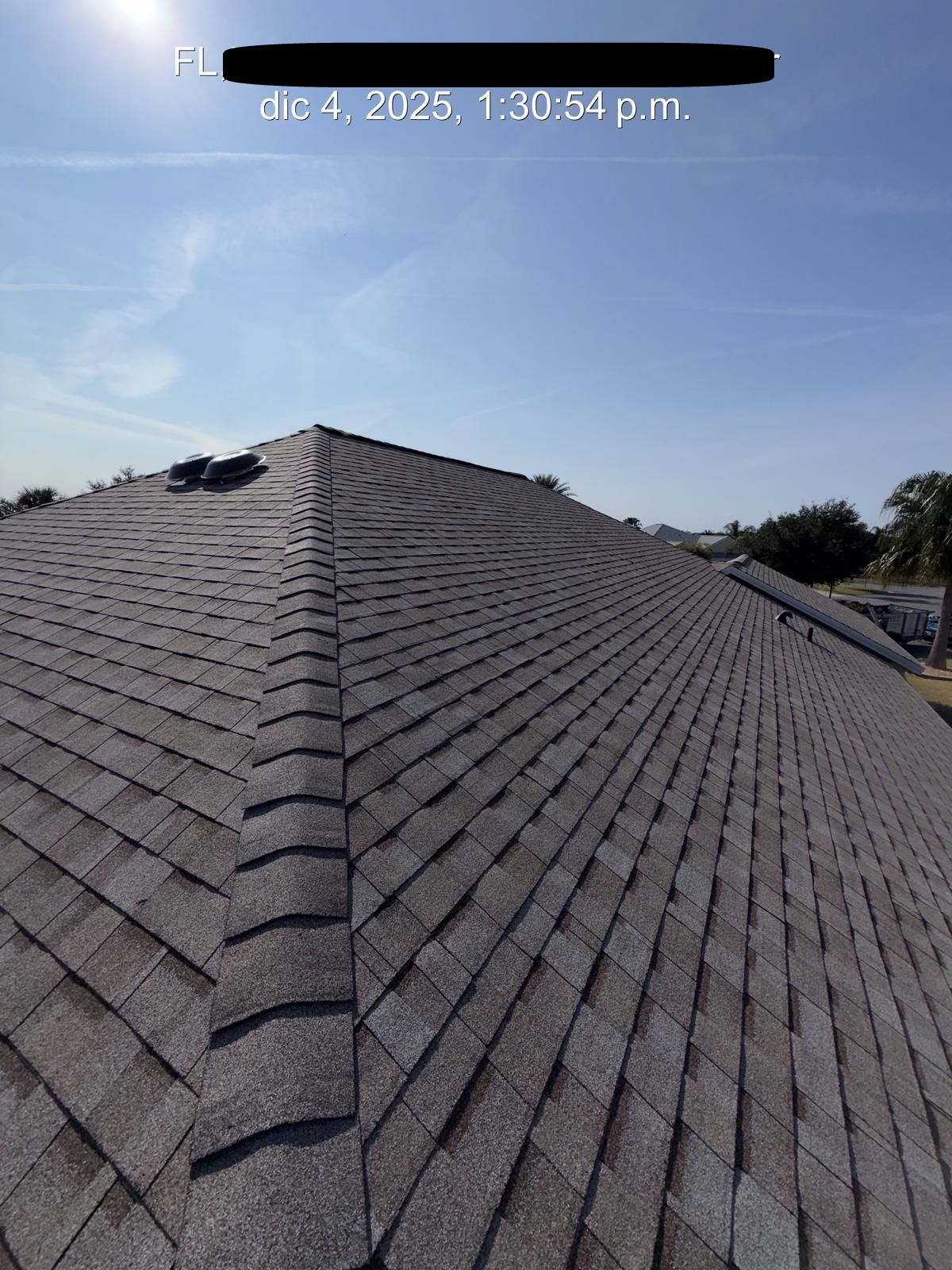 Roof with asphalt shingles under a clear, blue sky.