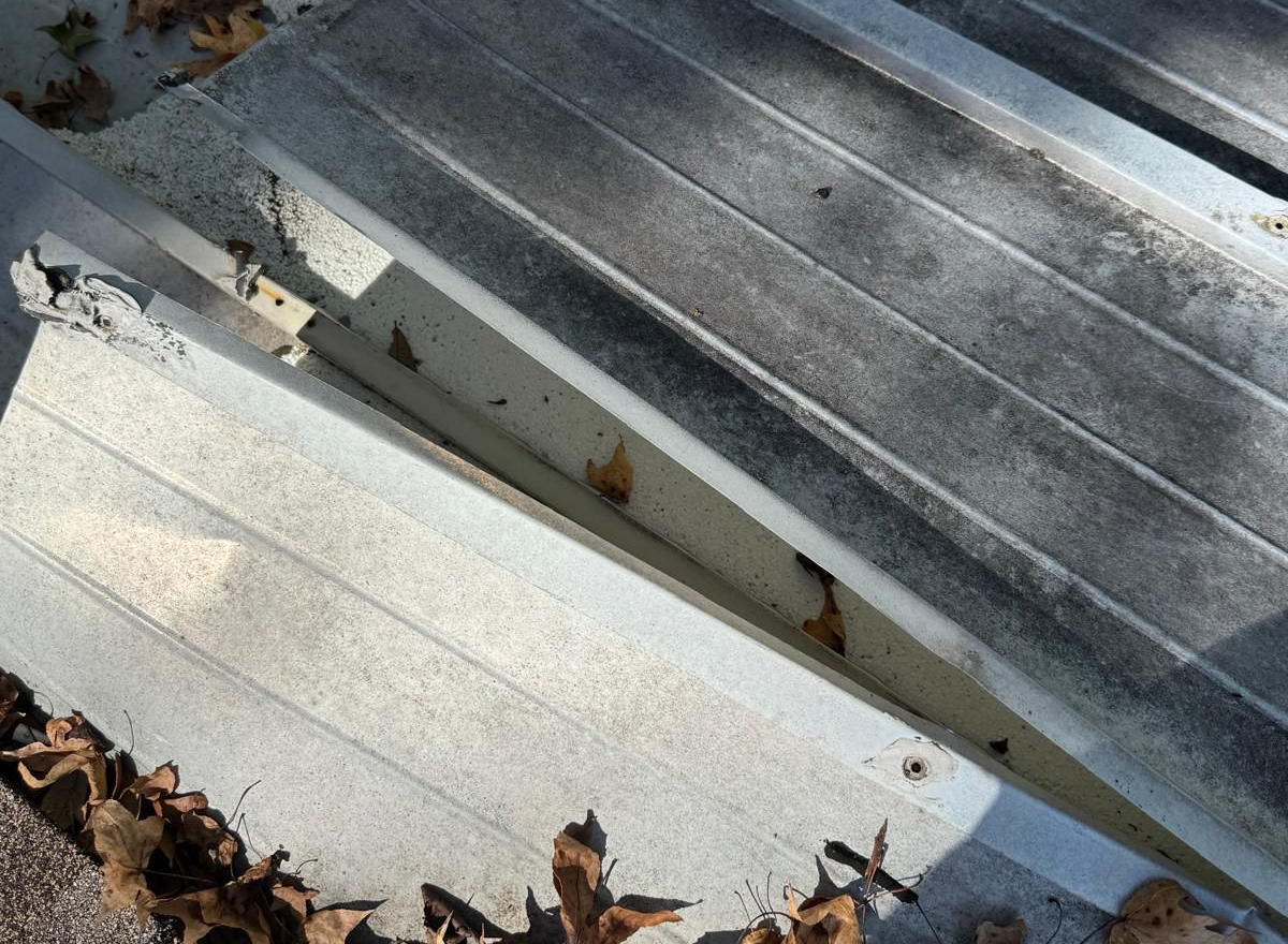 Damaged metal ramp with broken concrete and debris.