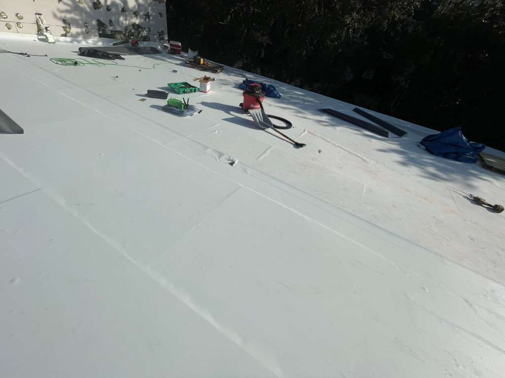 White flat roof with tools, possibly under construction, on a sunny day.