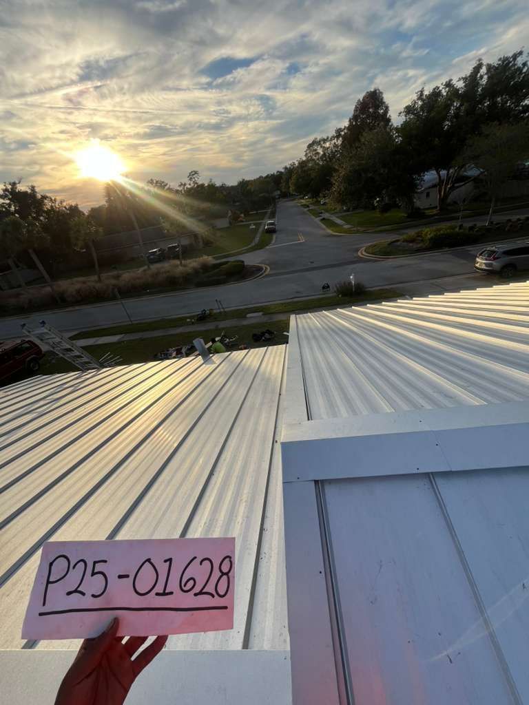 View from a metal roof overlooking a residential street at sunset; a hand holds a sign labeled "P25-01628".