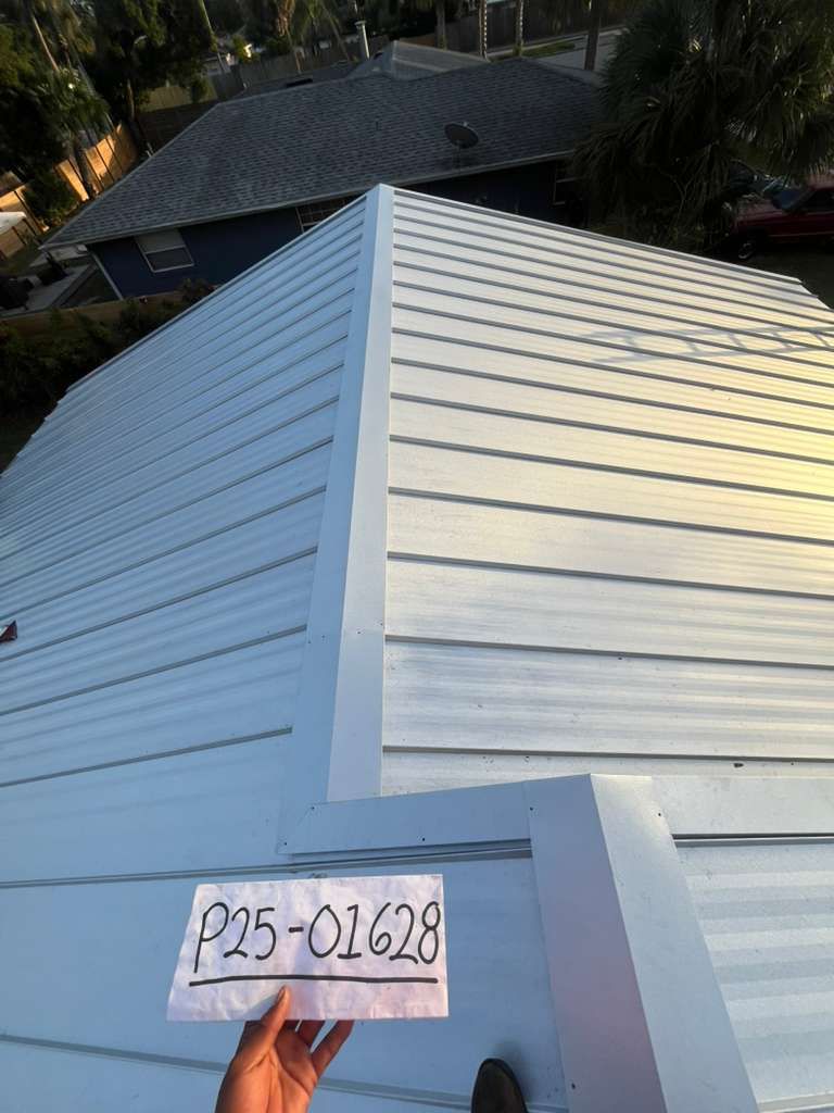 Close-up view of a light-colored metal roof with a person holding a sign. The roof is on a building.