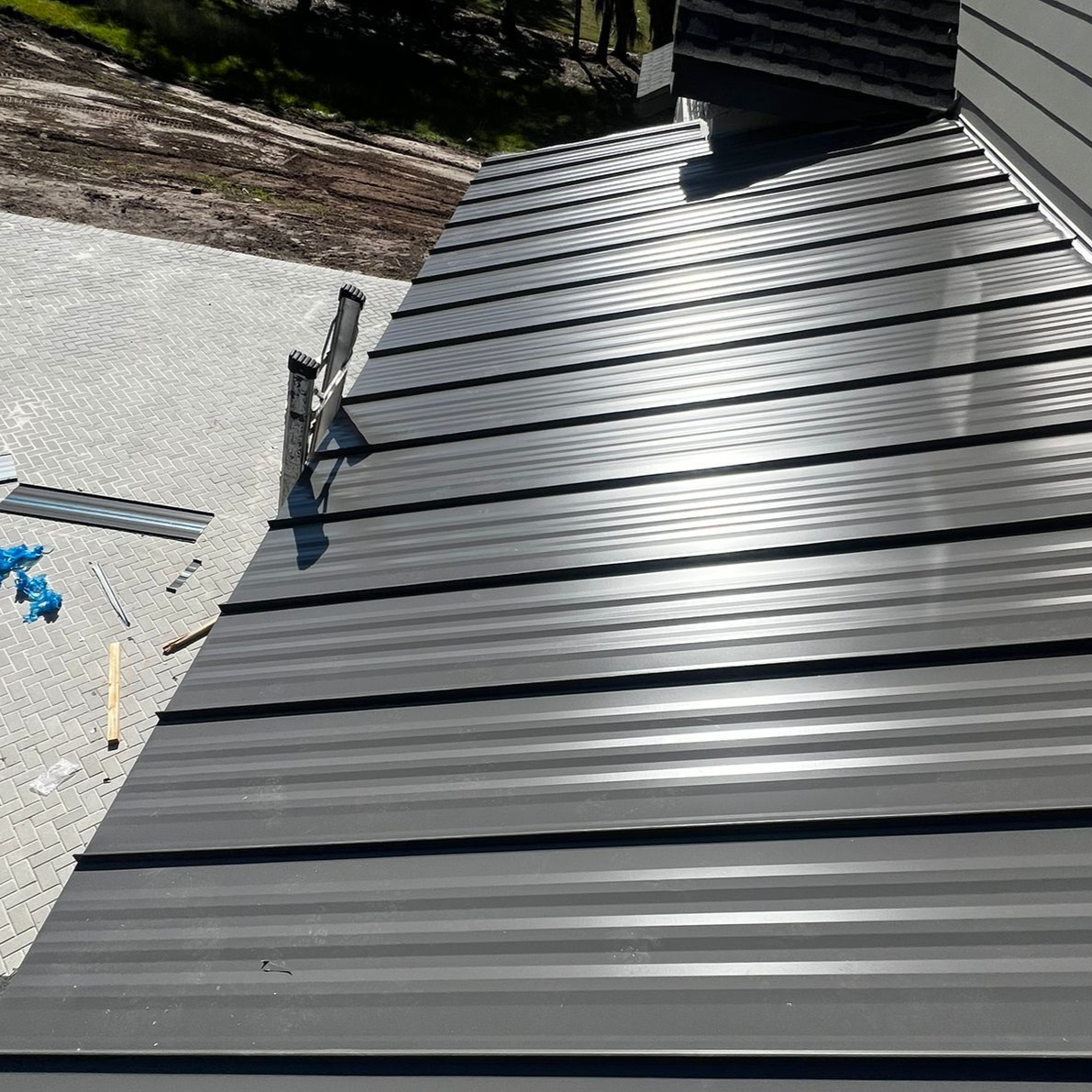 Dark gray metal roof angled view, with a gravel area to the left.
