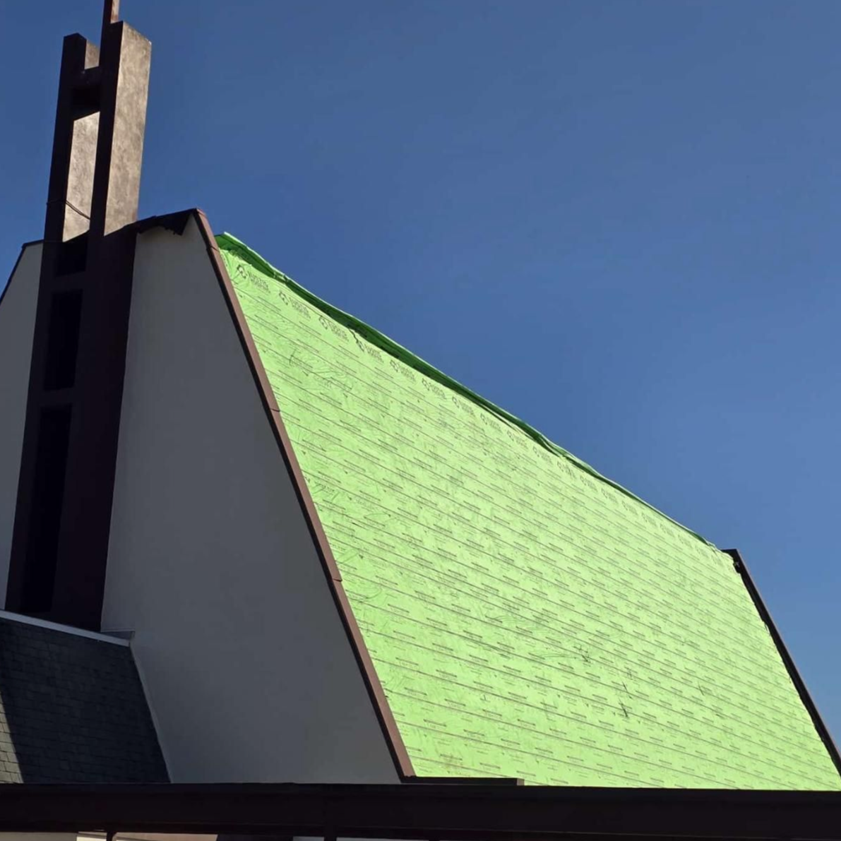 Green-roofed building against a blue sky, with a dark steeple at the top.