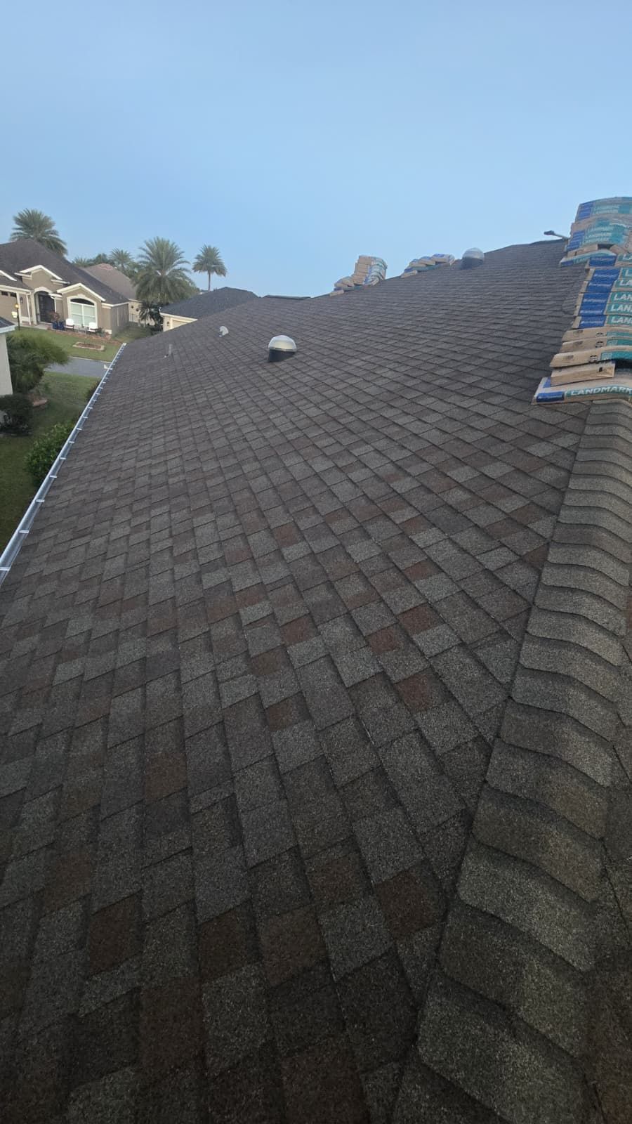 A residential roof with asphalt shingles. The shingles are mostly shades of brown.