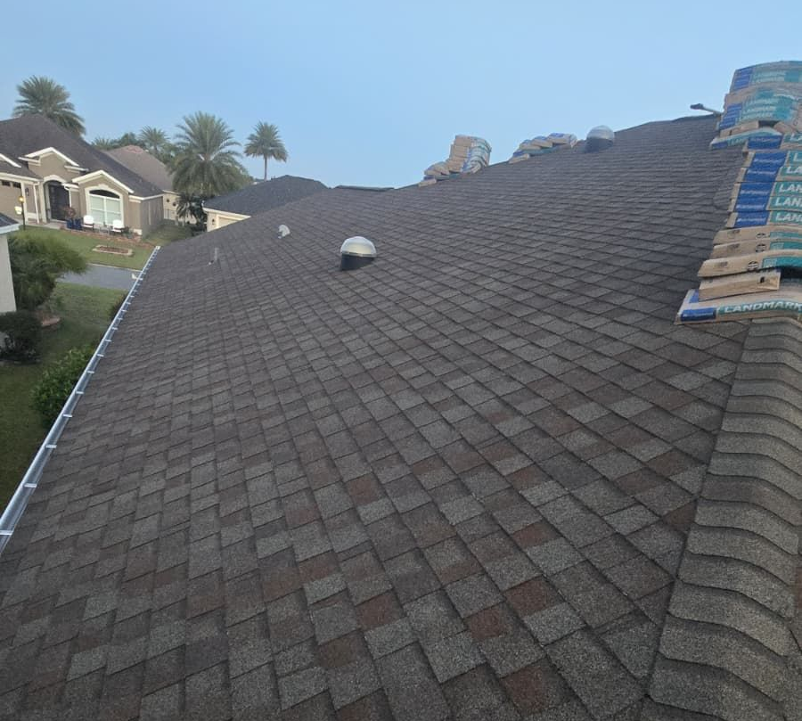 Dark brown shingle roof with vents, partially completed, overlooking a residential neighborhood.