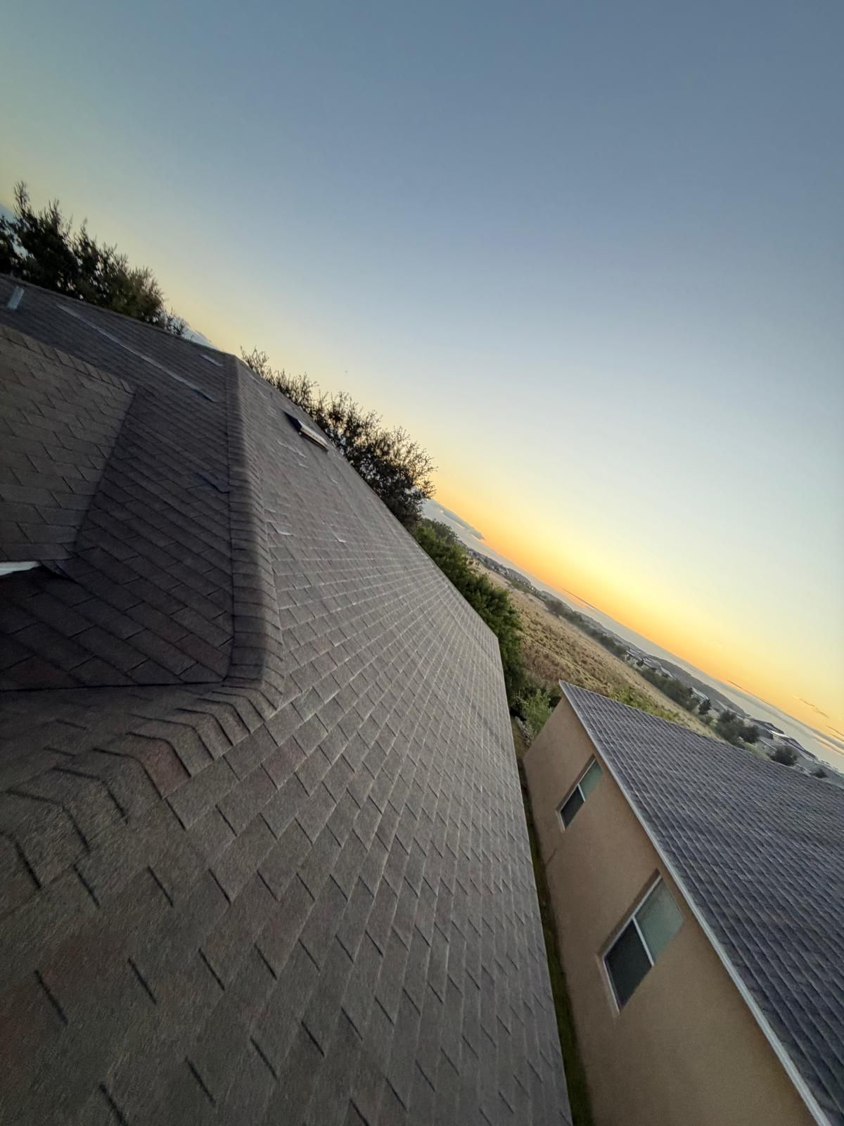 A roof of a house at sunrise with a blue and yellow sky.