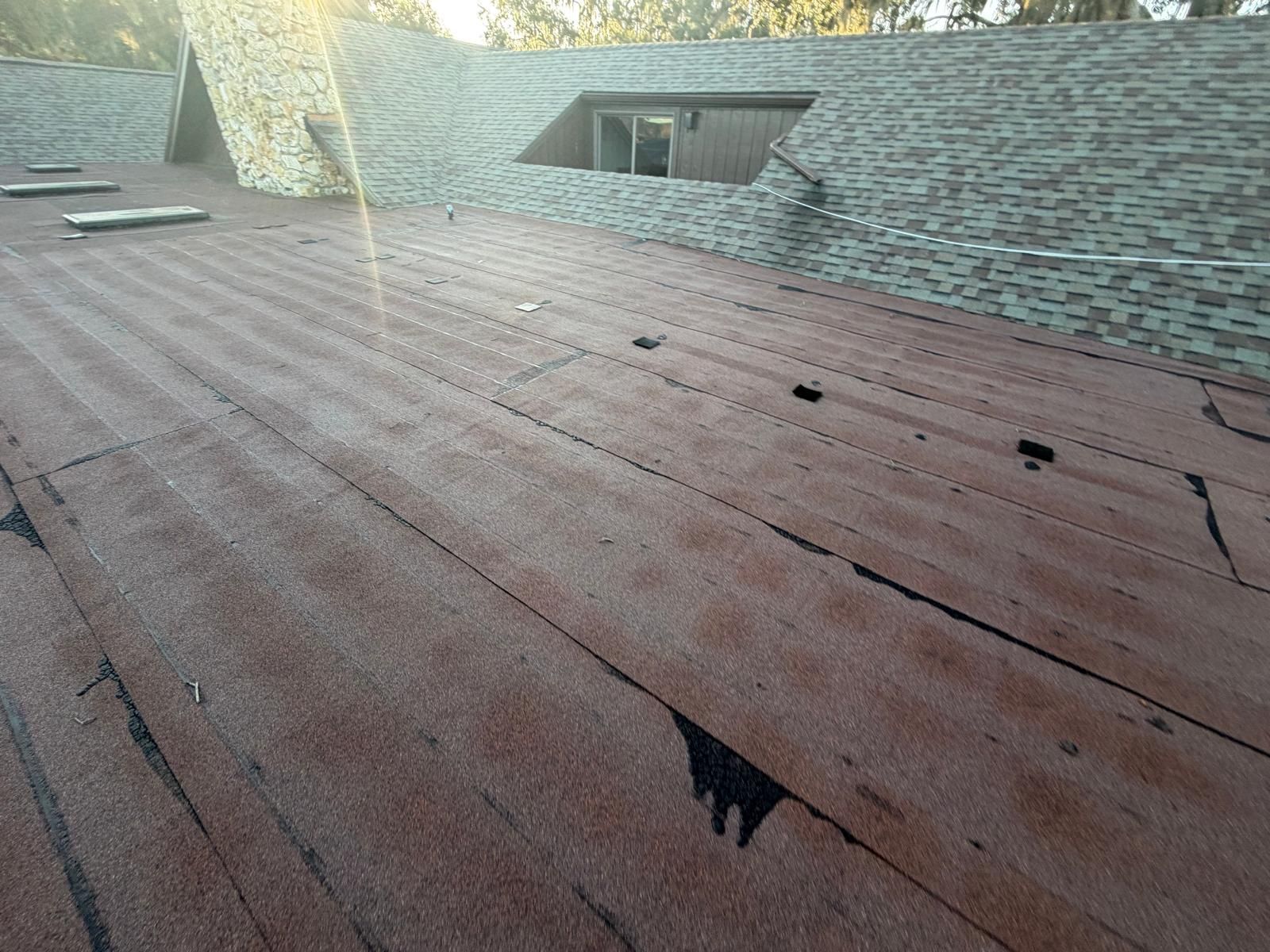 A roof with wood-like pattern, with sections missing or damaged. Some areas have dark patches.