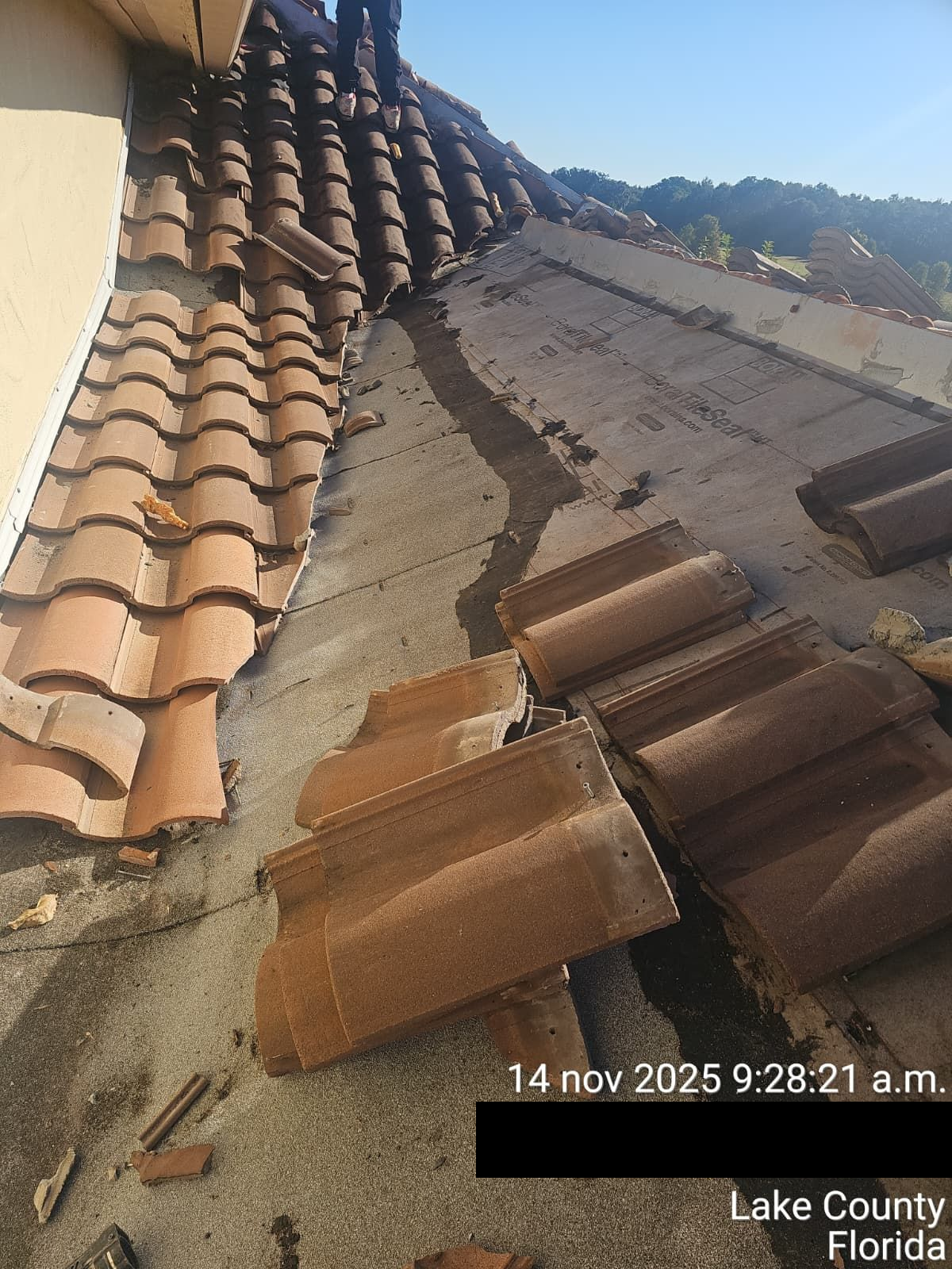 Damaged clay tile roof with fallen tiles, visible concrete underlayment, Lake County, Florida.