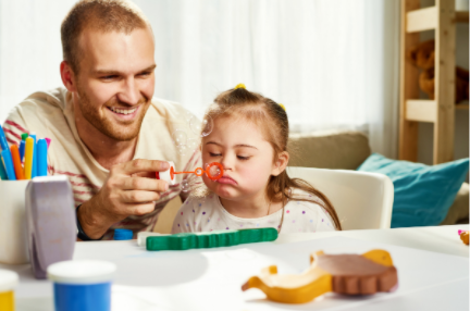 Adult and child making crafts at a table with colorful supplies, smiling indoors