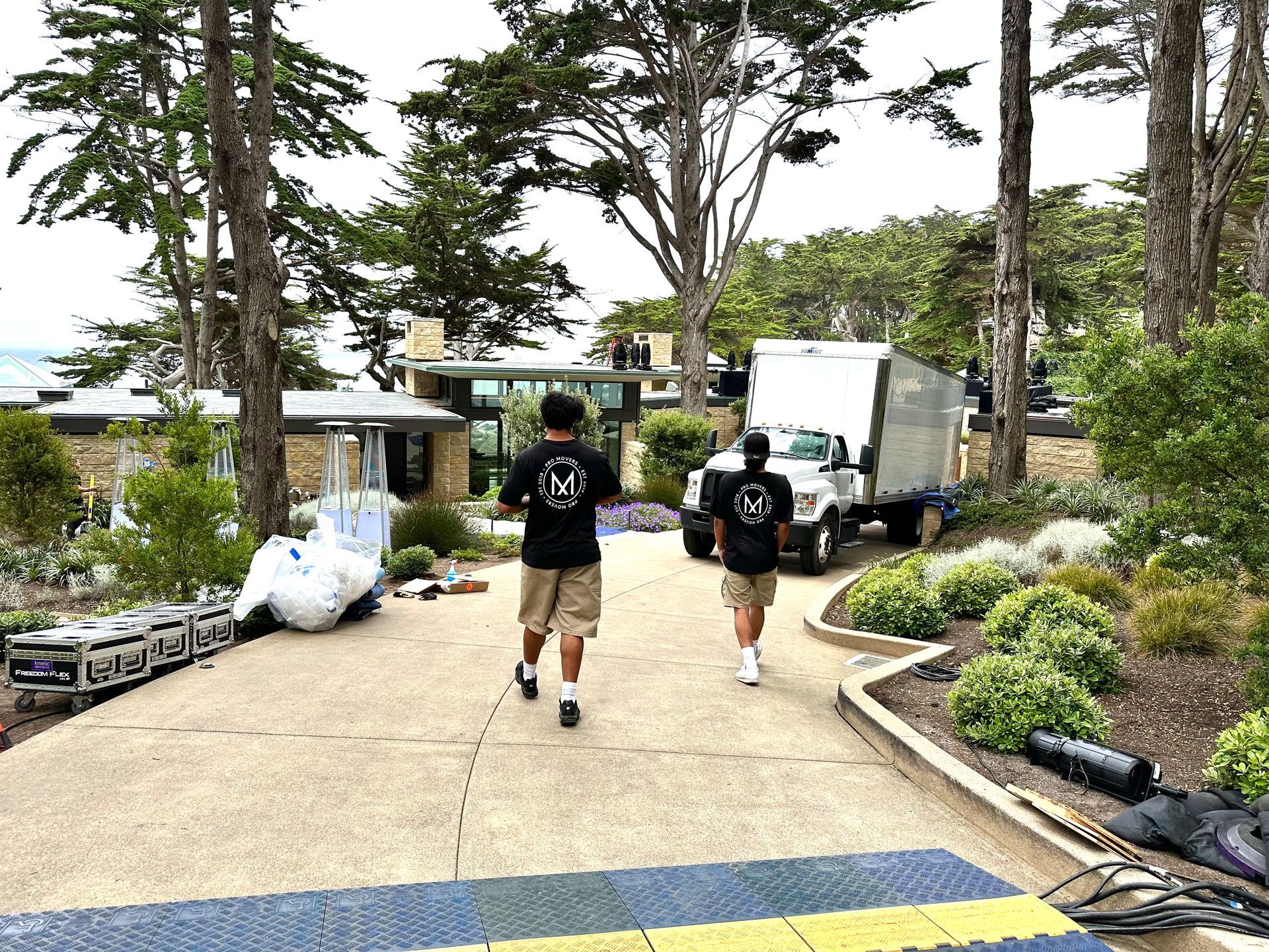 Two men are walking down a driveway next to a truck.