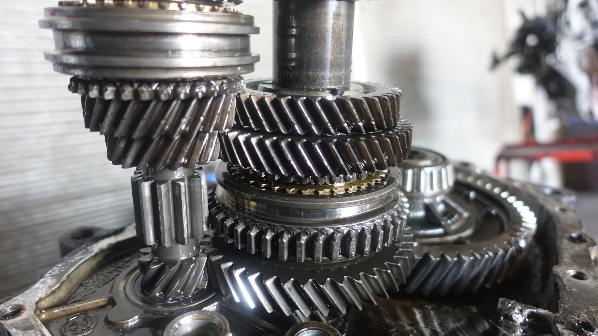 Close-up of interlocking metal gears and shafts with oily, industrial machinery parts