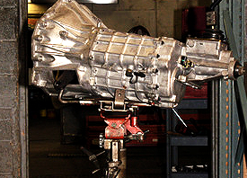 Metal gearbox or transmission mounted on a stand in a workshop.
