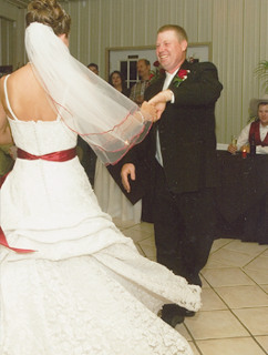 A bride and groom are dancing at their wedding reception