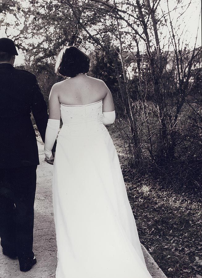 A black and white photo of a bride and groom walking down a path