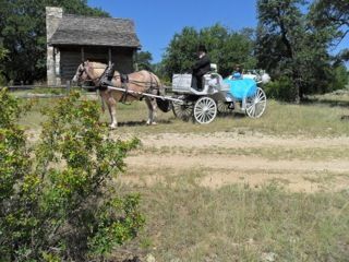 A horse drawn carriage is driving down a dirt road.