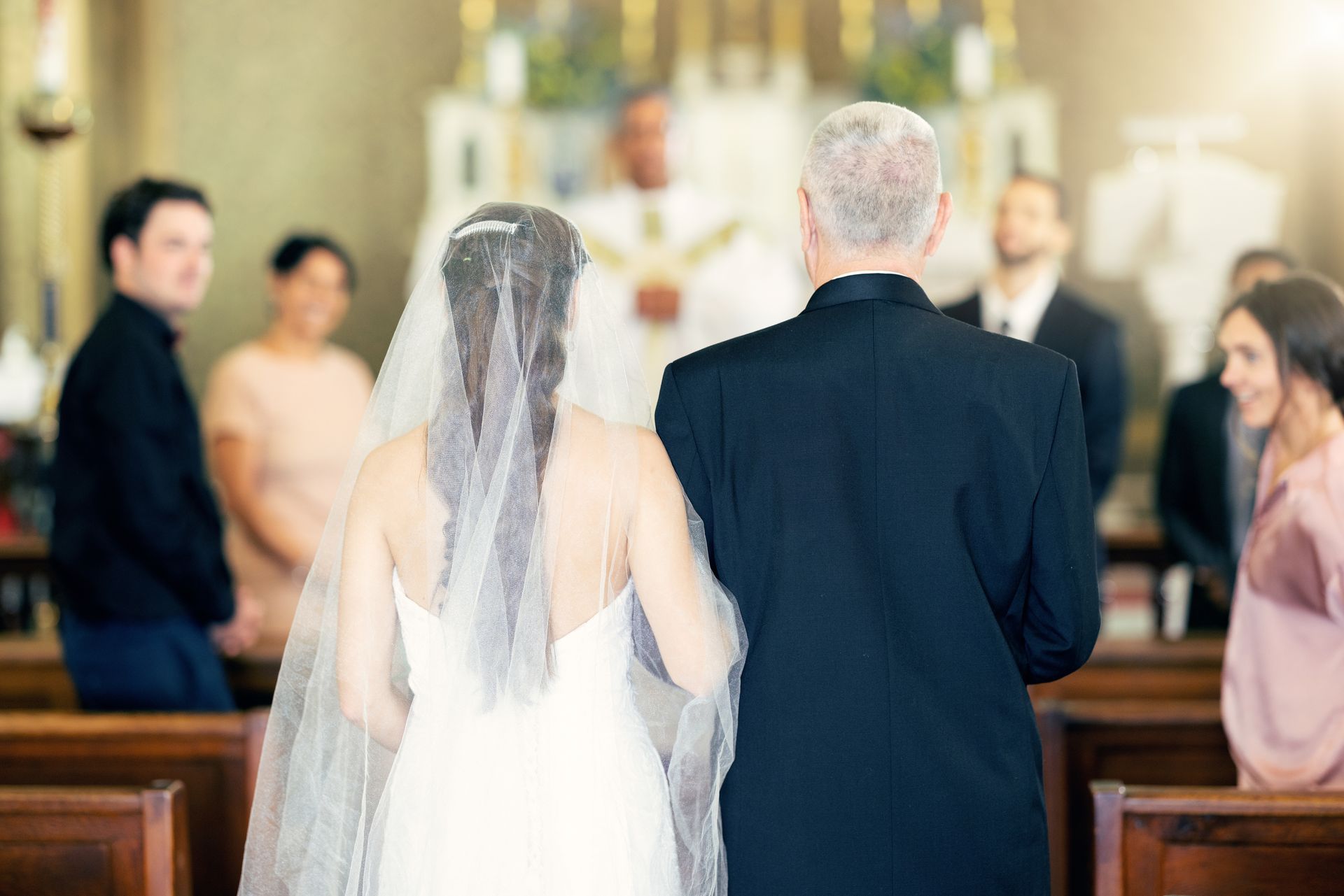 A bride and her father are walking down the aisle of a church.