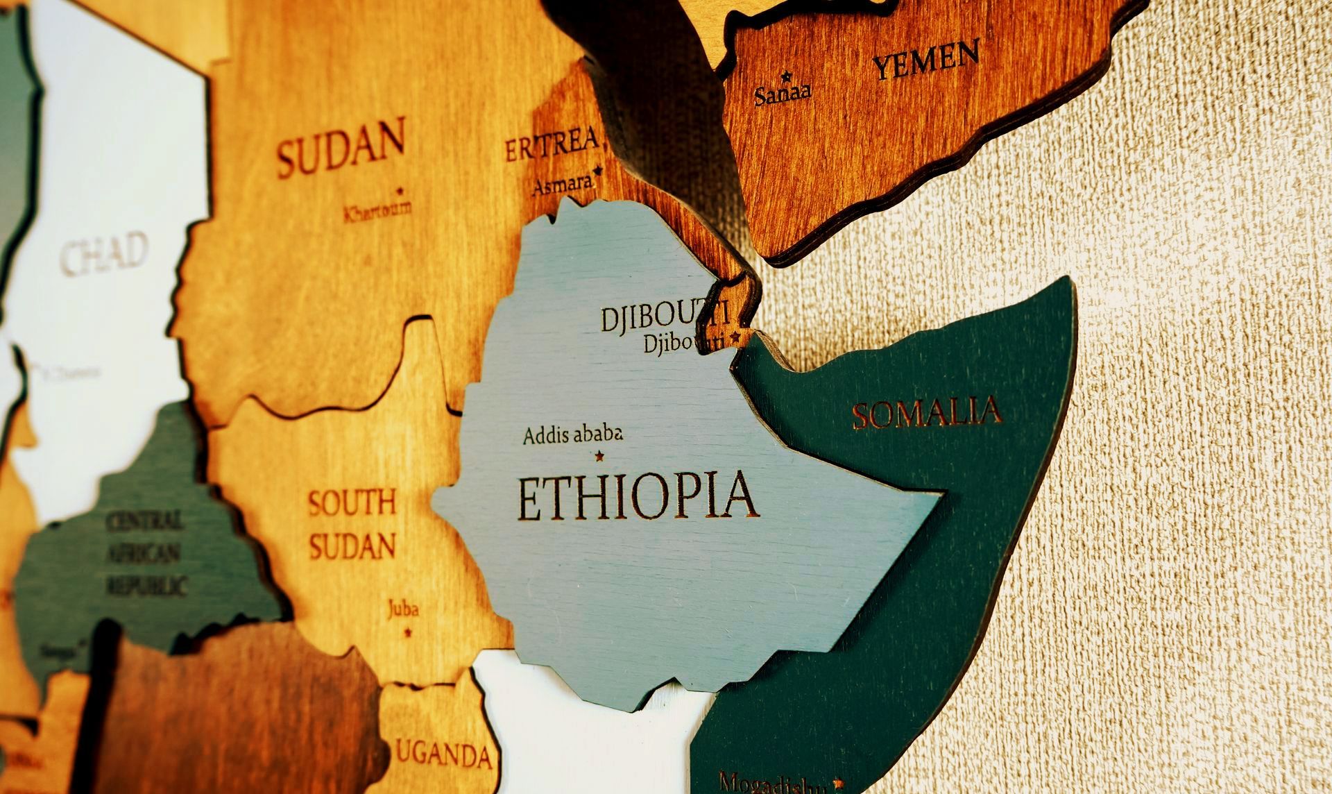 Wooden map of Africa highlighting Ethiopia in blue-green, surrounded by various brown countries.