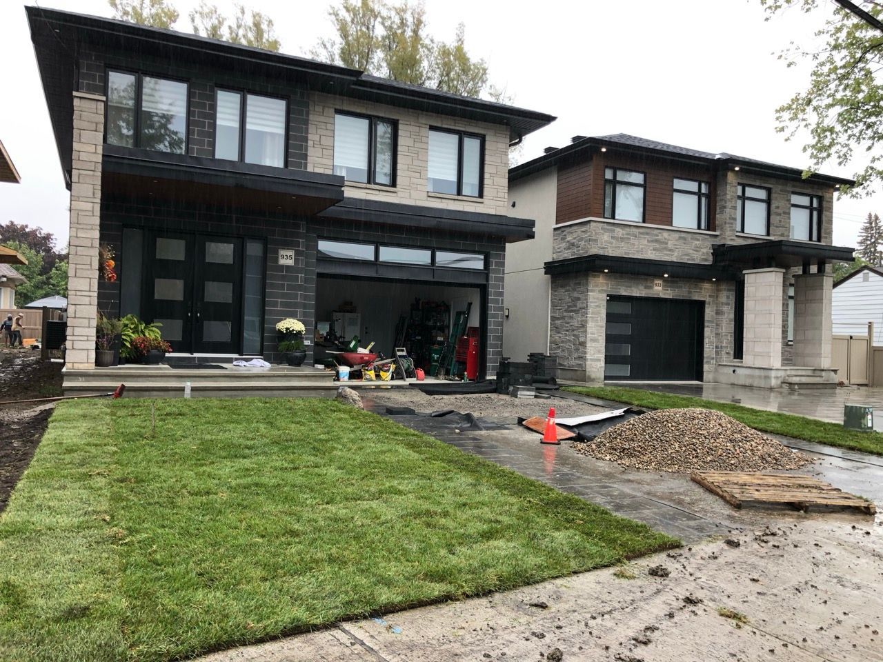 Deux maisons modernes avec de nouvelles pelouses vertes et des matériaux de construction dans l'allée.