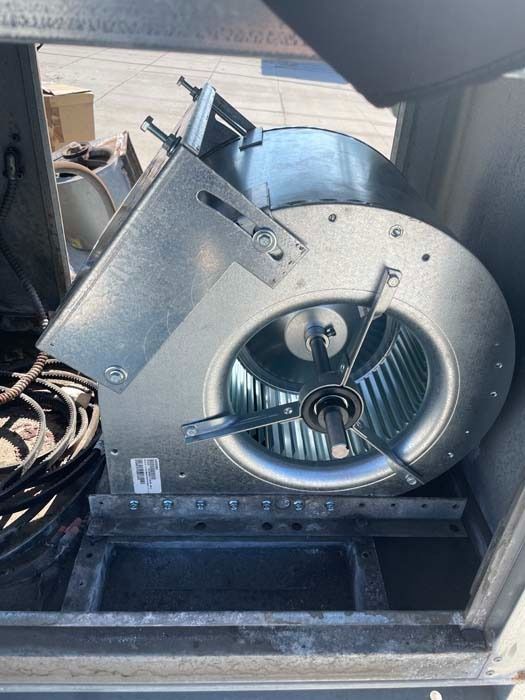 A metallic blower fan assembly inside a heating and air conditioning unit.