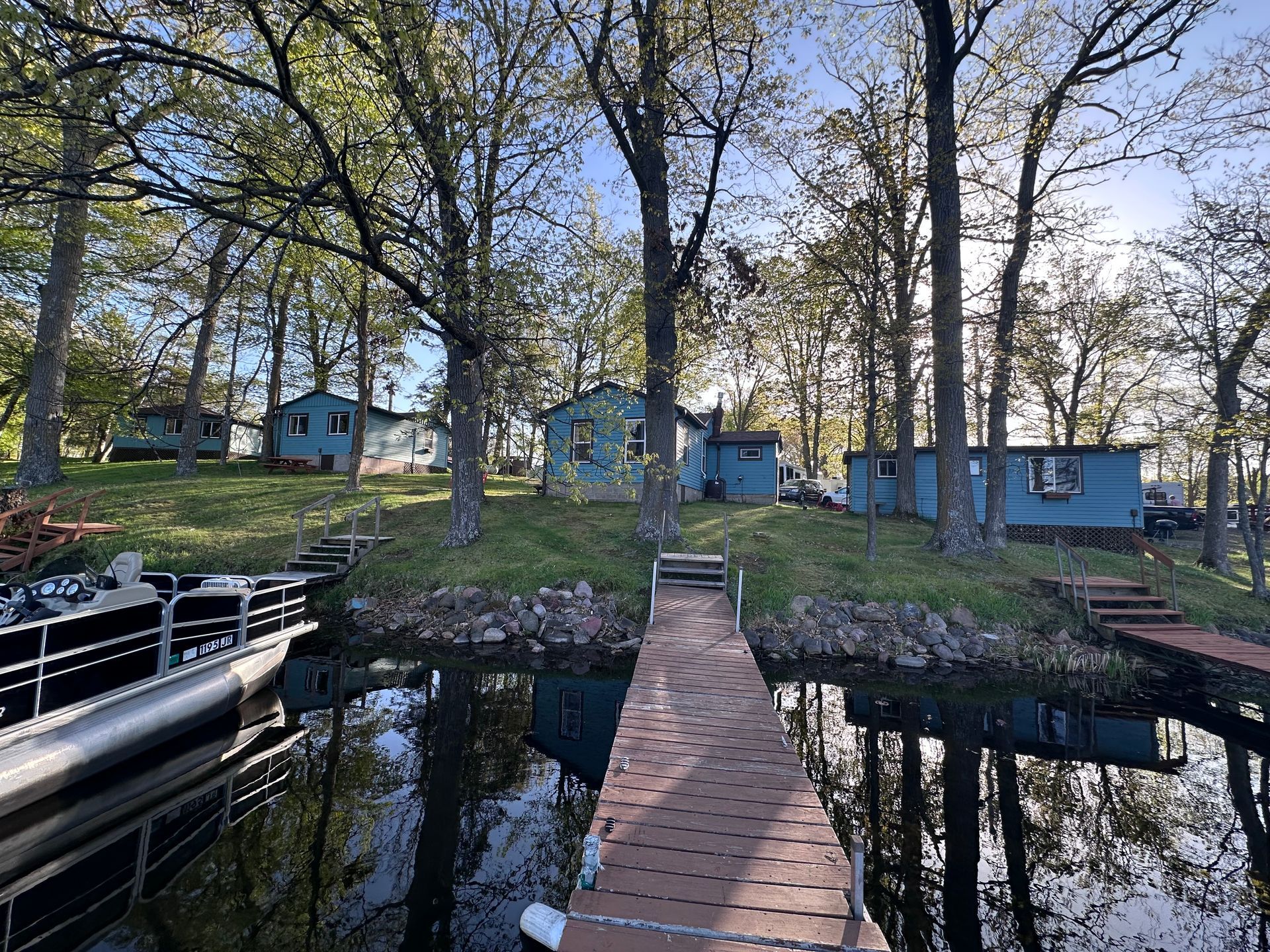 Lake view through a window, with boats docked below and trees lining the shore.