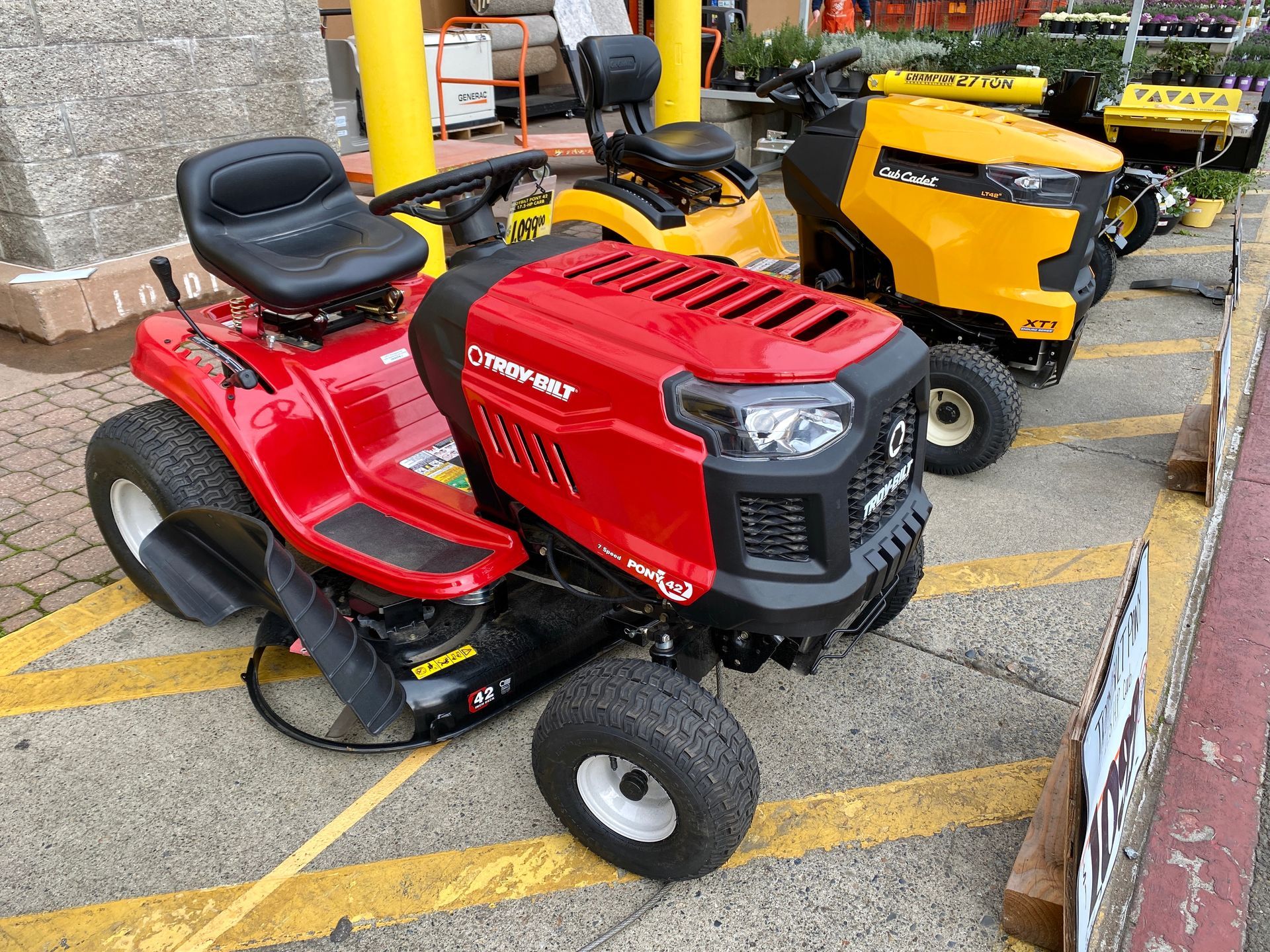 Red Craftsman riding lawn tractor parked beside a yellow mower on a striped outdoor lot.
