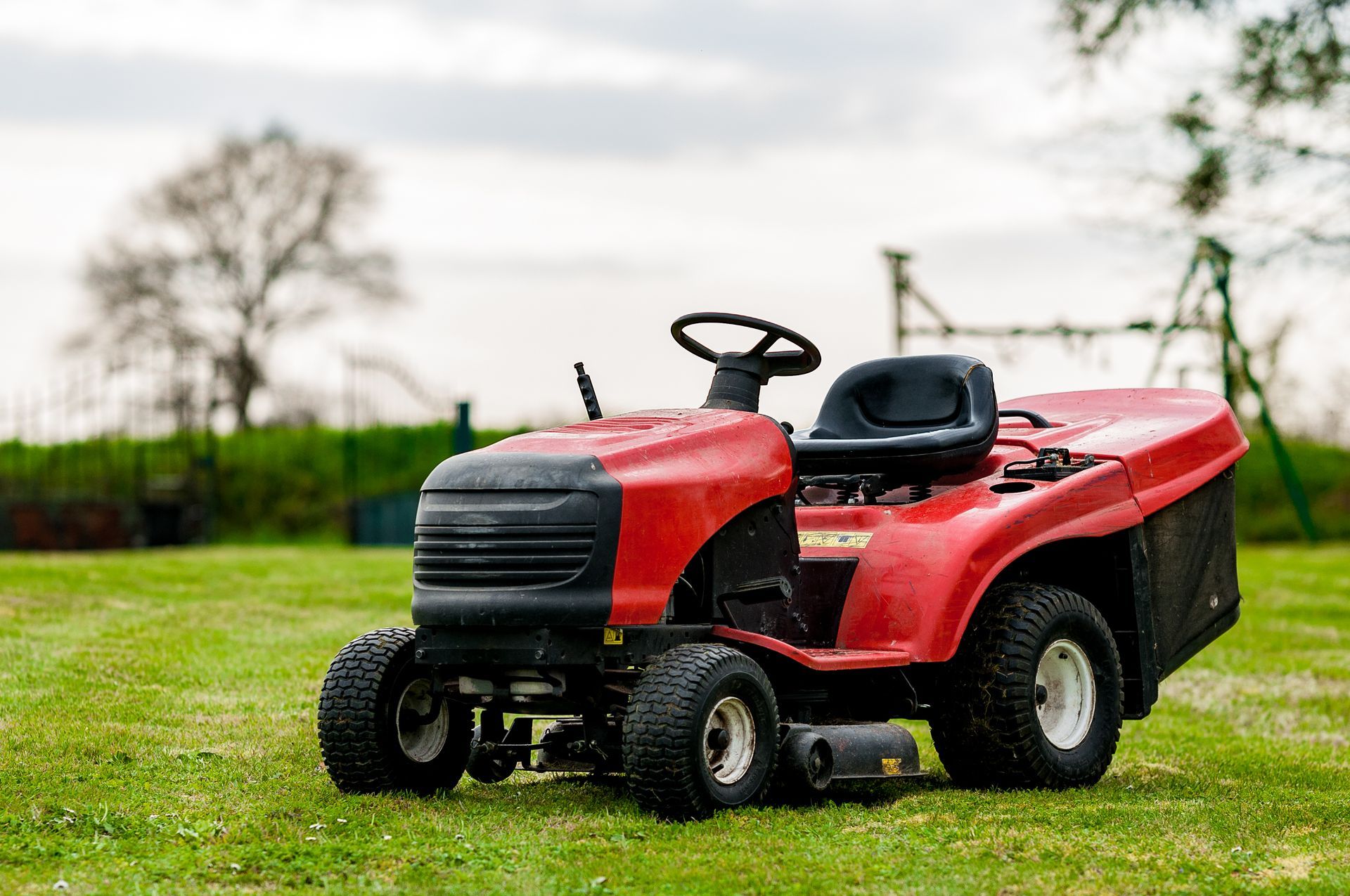 Red riding lawn mower on green grass in a yard