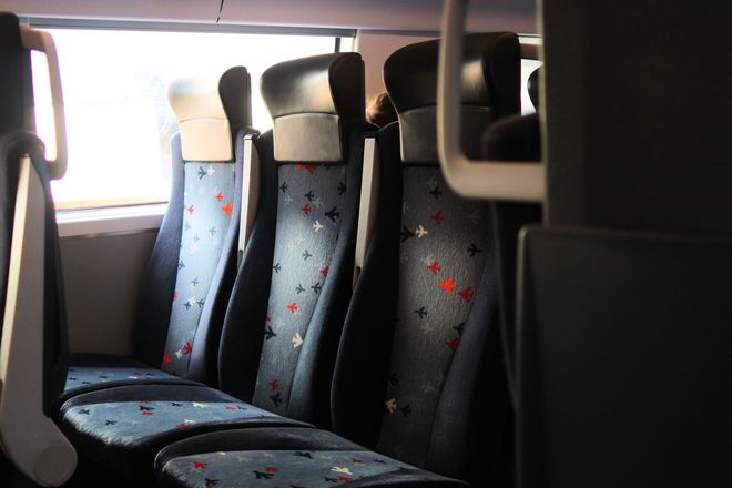 Empty bus seats with blue patterned fabric by a bright window