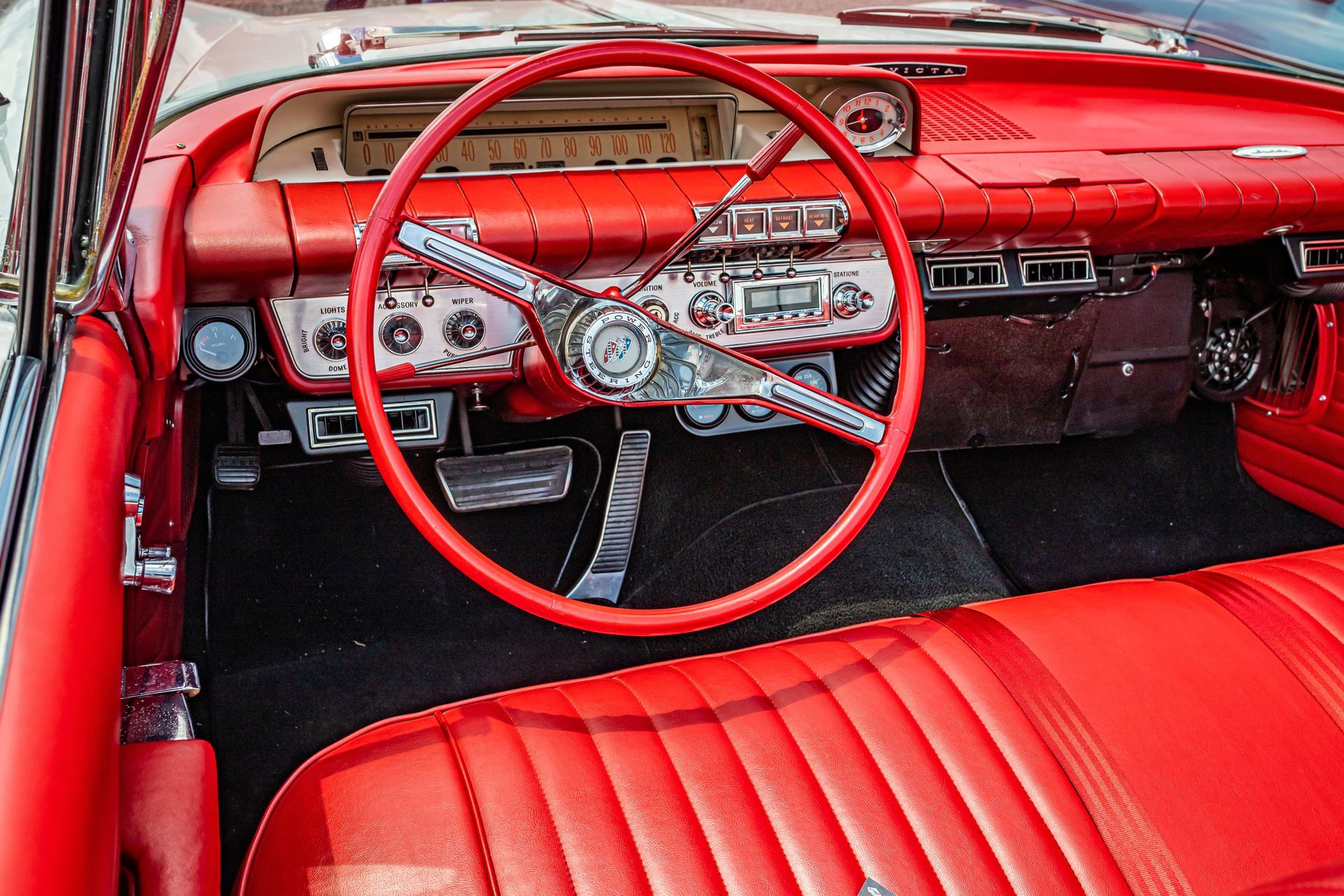 Red vintage car interior with red steering wheel, dashboard, and red bench seat