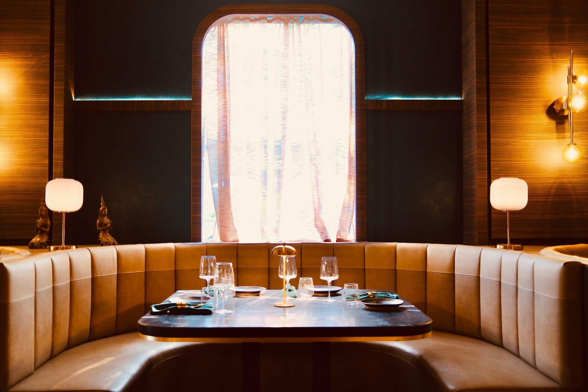 Cozy booth seating around a restaurant table with glassware and warm wall sconces at dusk