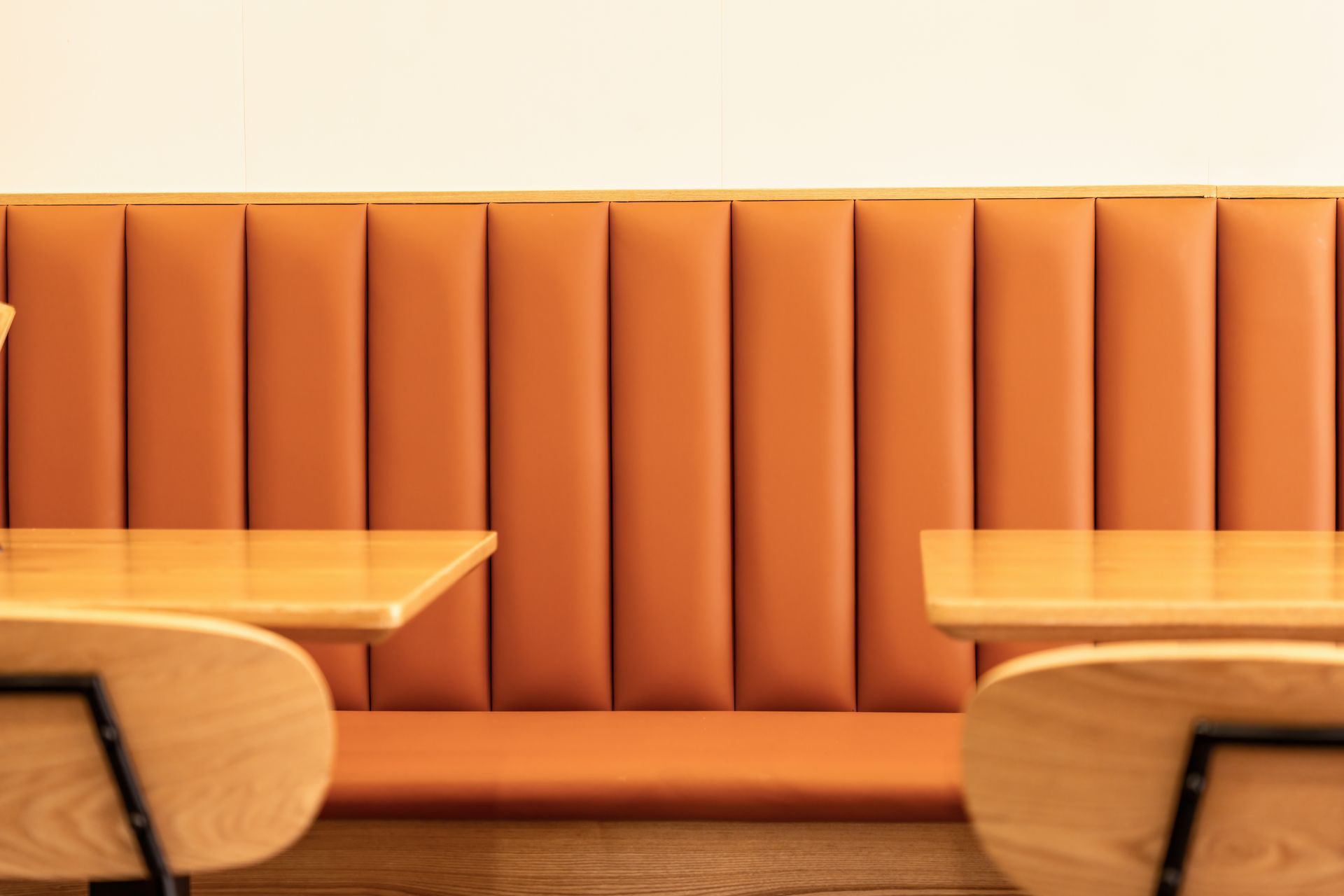 Orange upholstered booth with wooden tables in a warm-lit restaurant interior