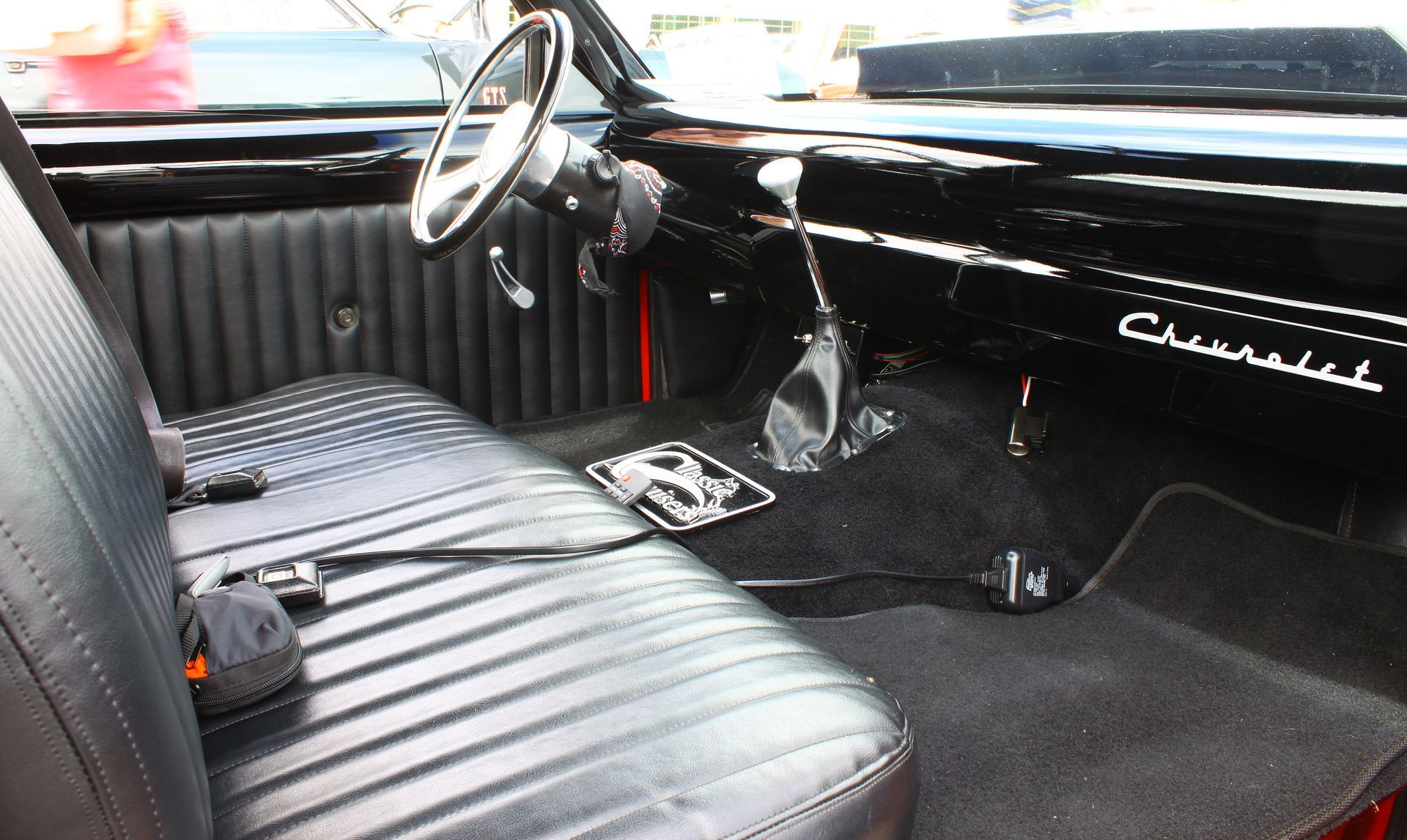 Vintage car interior with black seats, steering wheel, and dashboard in a dimly lit cabin