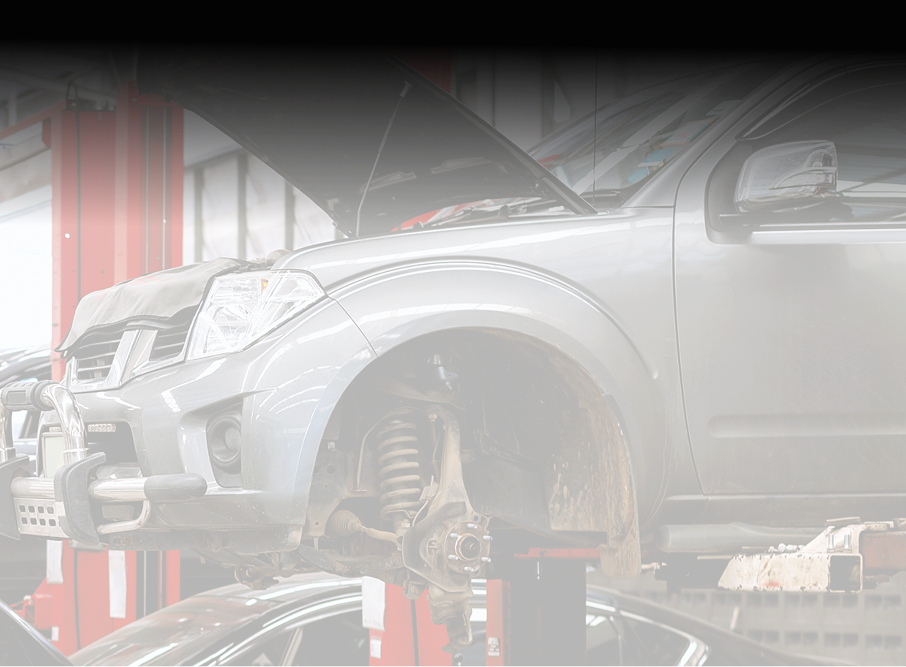 Silver truck raised on a lift in a repair shop, hood open for maintenance  - A&H Automotive Repair Shop