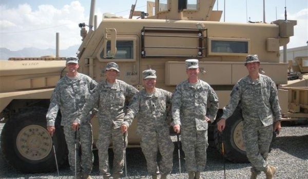 A group of soldiers standing in front of a military vehicle