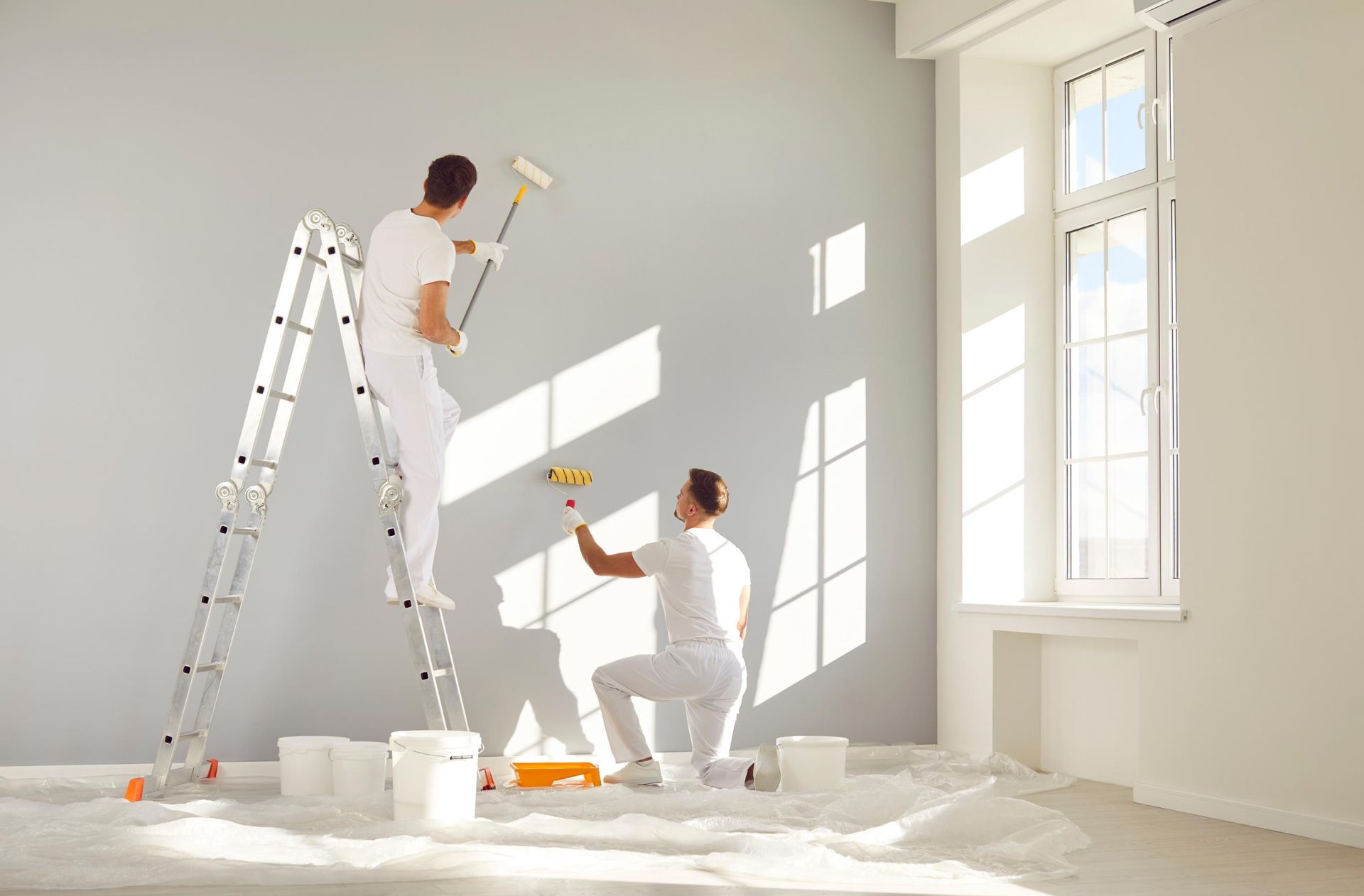 Two Men Are Painting A Wall In An Empty Room — Strait Edge Painting In Byron Bay, NSW