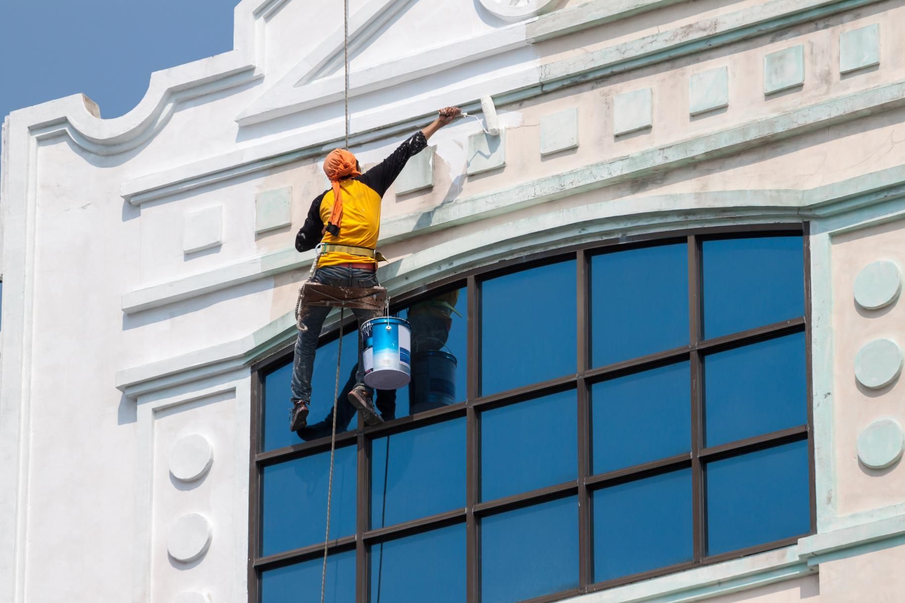 A Man Is Painting The Walls Of A Tall Building — Strait Edge Painting In Tweed Heads, NSW