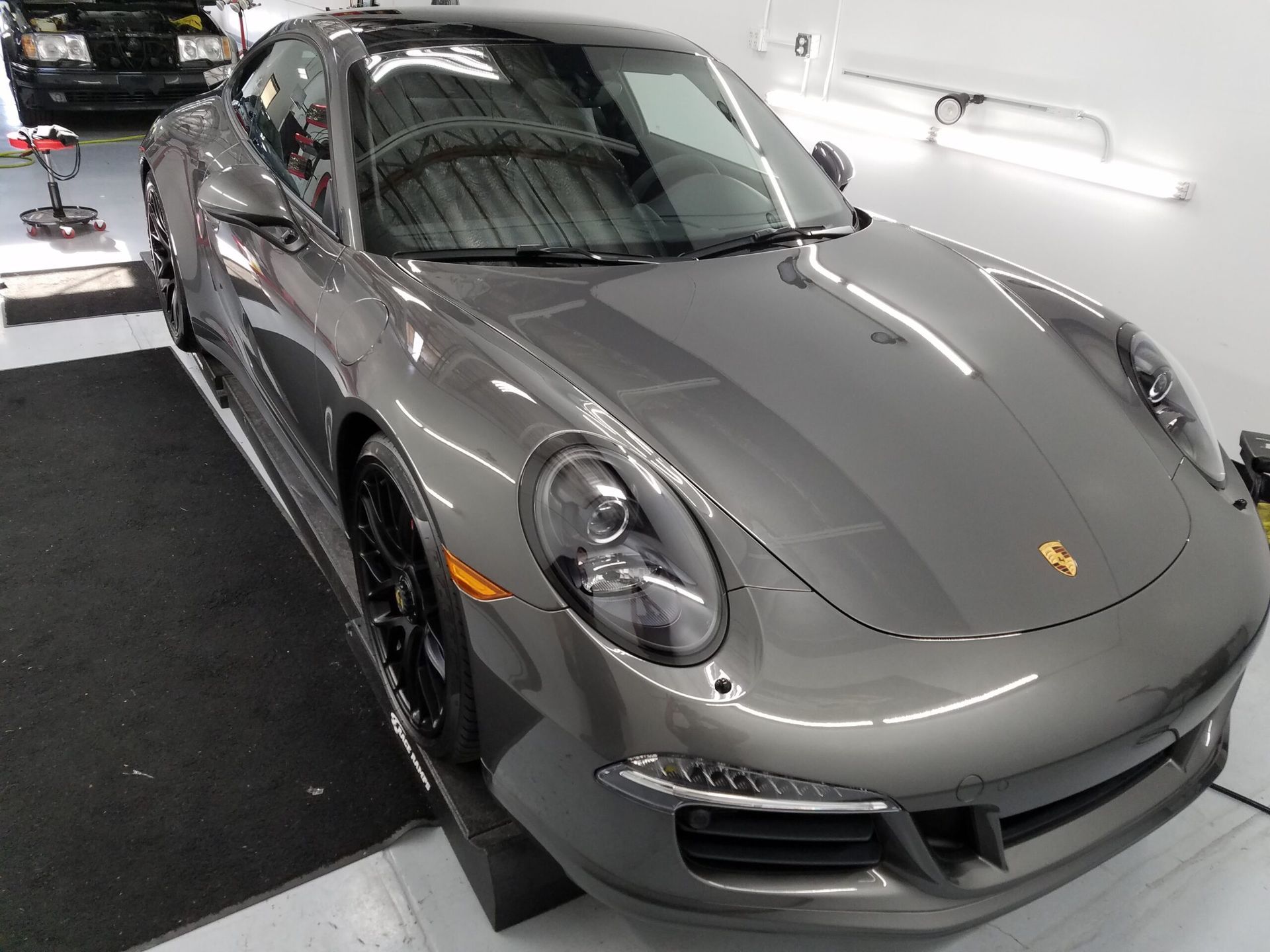 Gray Porsche sports car parked indoors under bright lights.