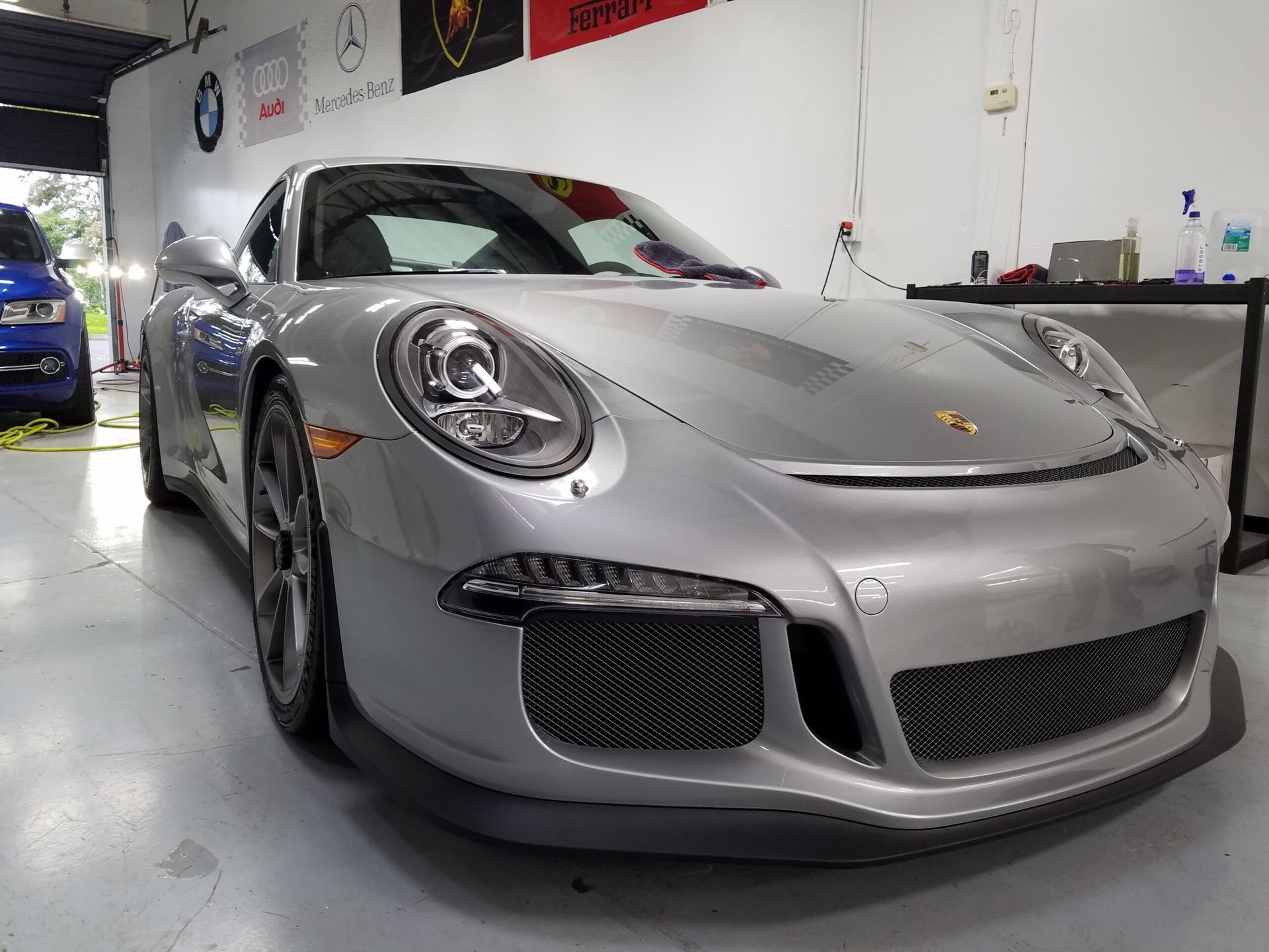 Silver Porsche 911 in a garage, front three-quarter view with custom body kit and dark grille
