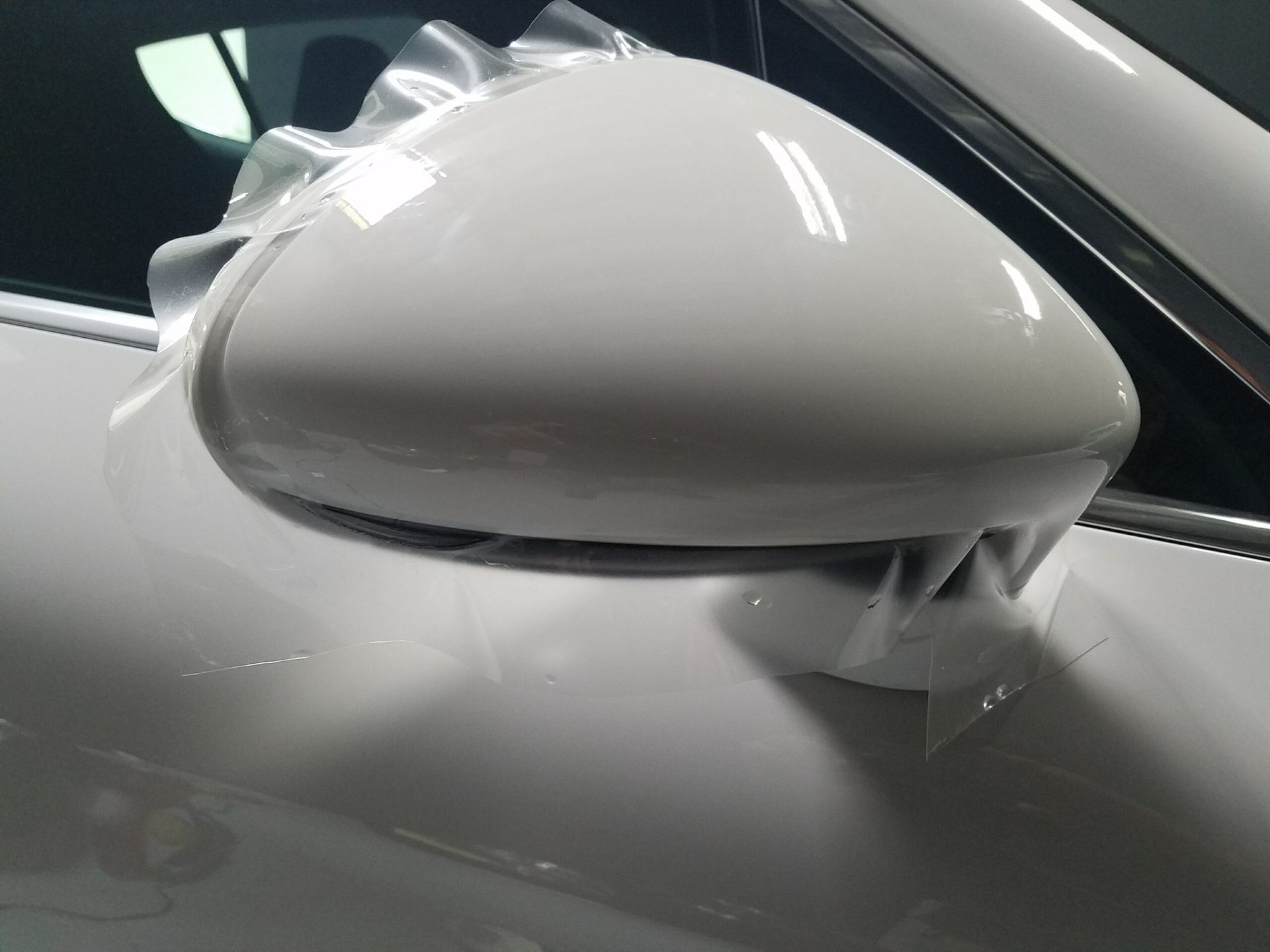 Close-up of a white car side mirror on a white vehicle