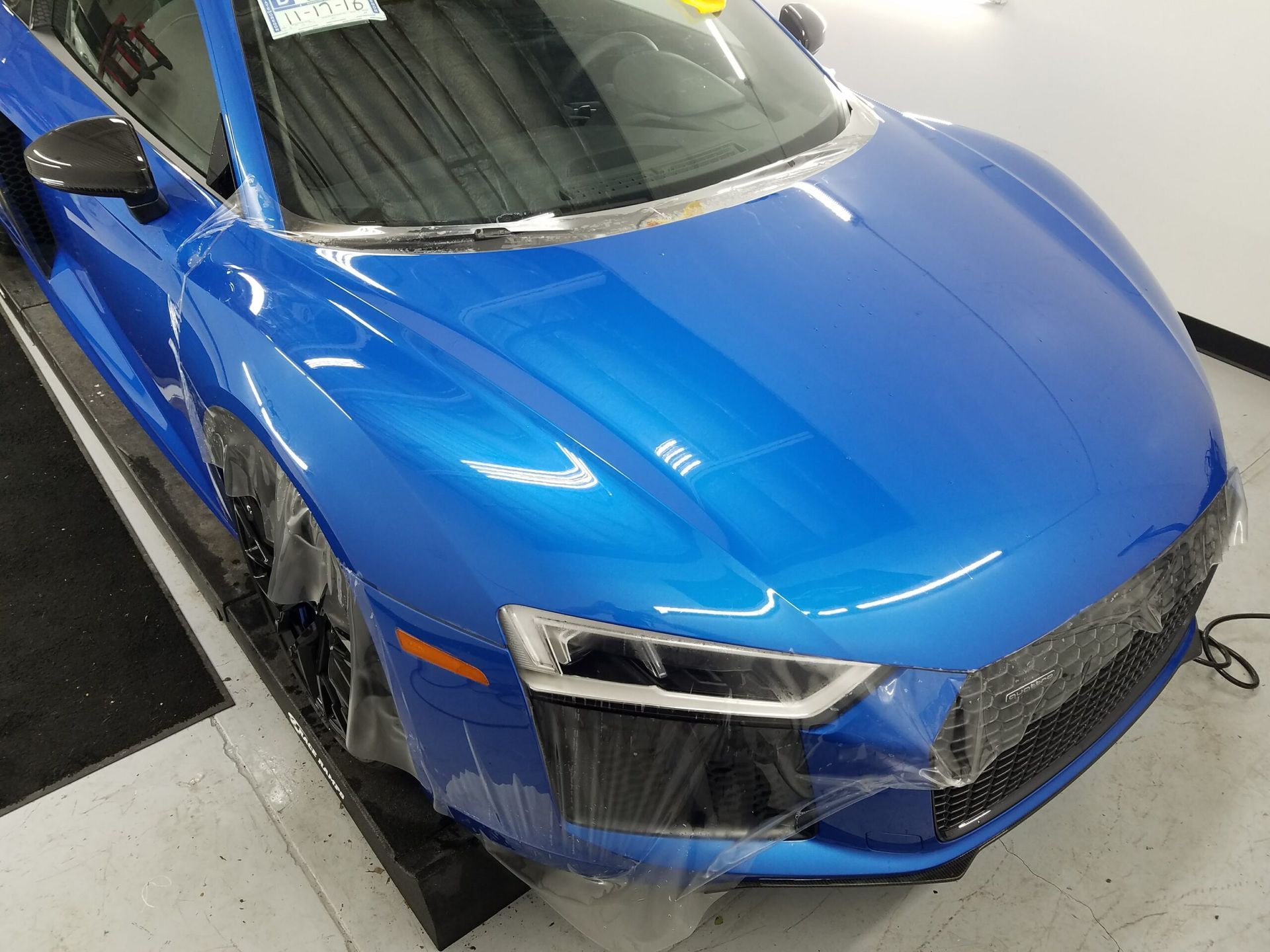 Blue sports car viewed from above in a garage, showing the hood and front headlights.