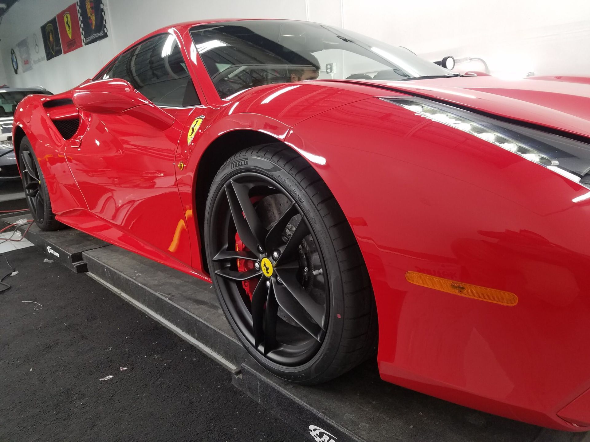 Red sports car in a garage, side view with black wheels and glossy finish