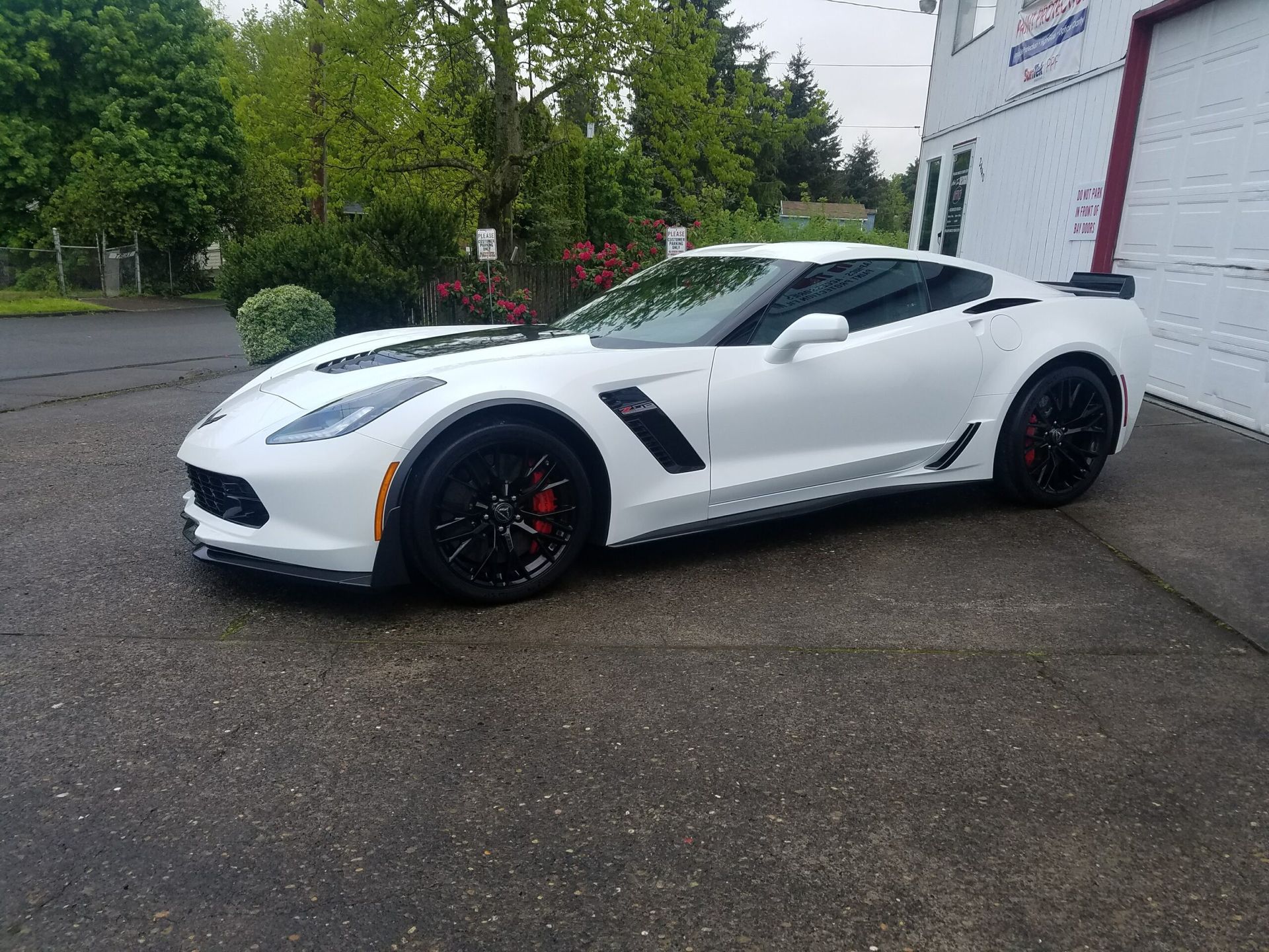 White sports car parked outside a building on a wet pavement