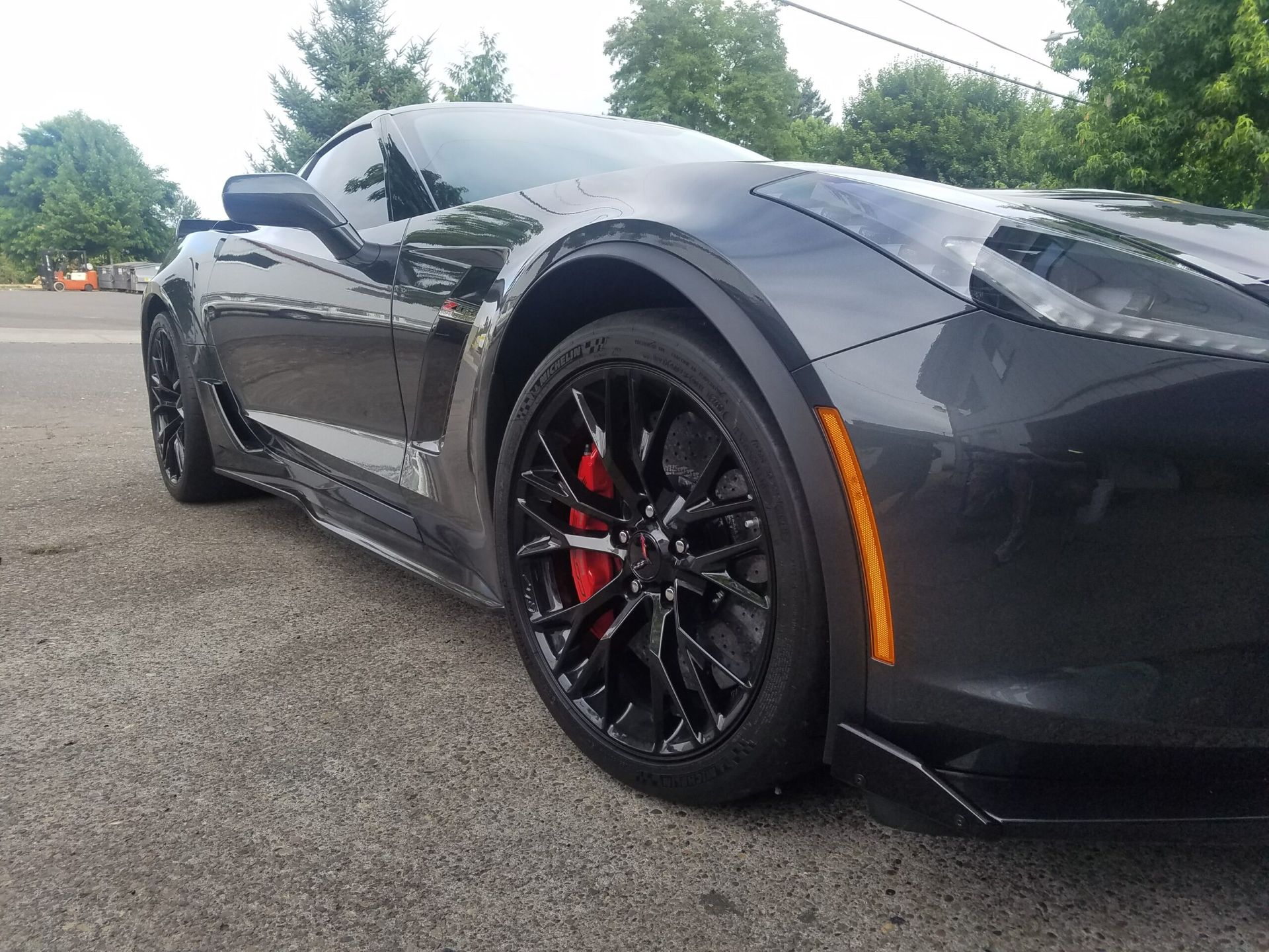 Black sports car with red brake calipers parked on a road, low side view