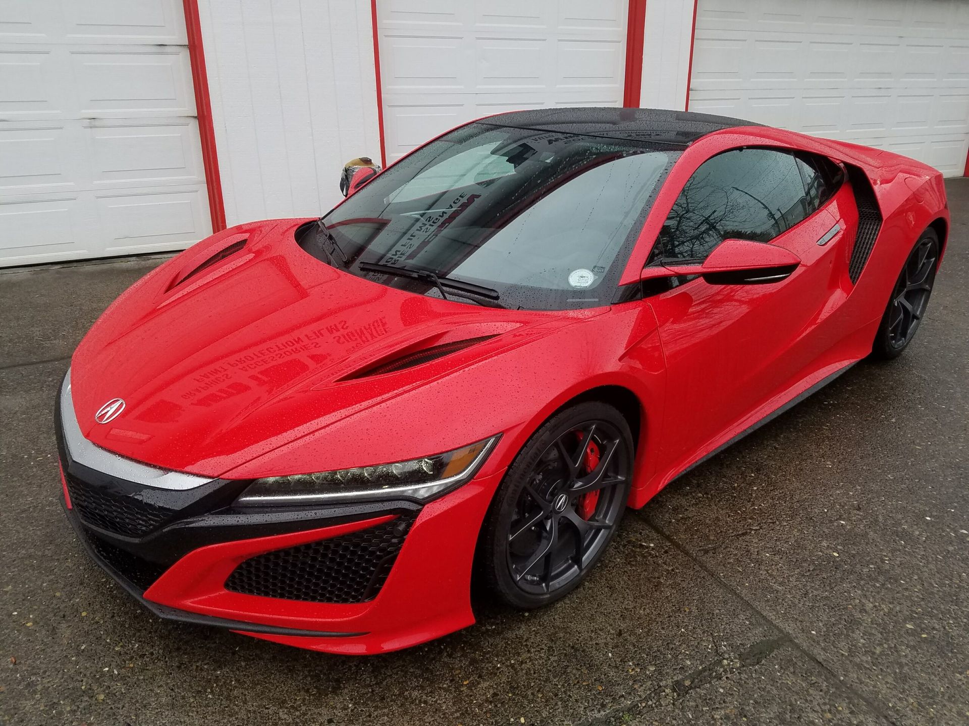 Red sports car parked outdoors in front of a white garage door