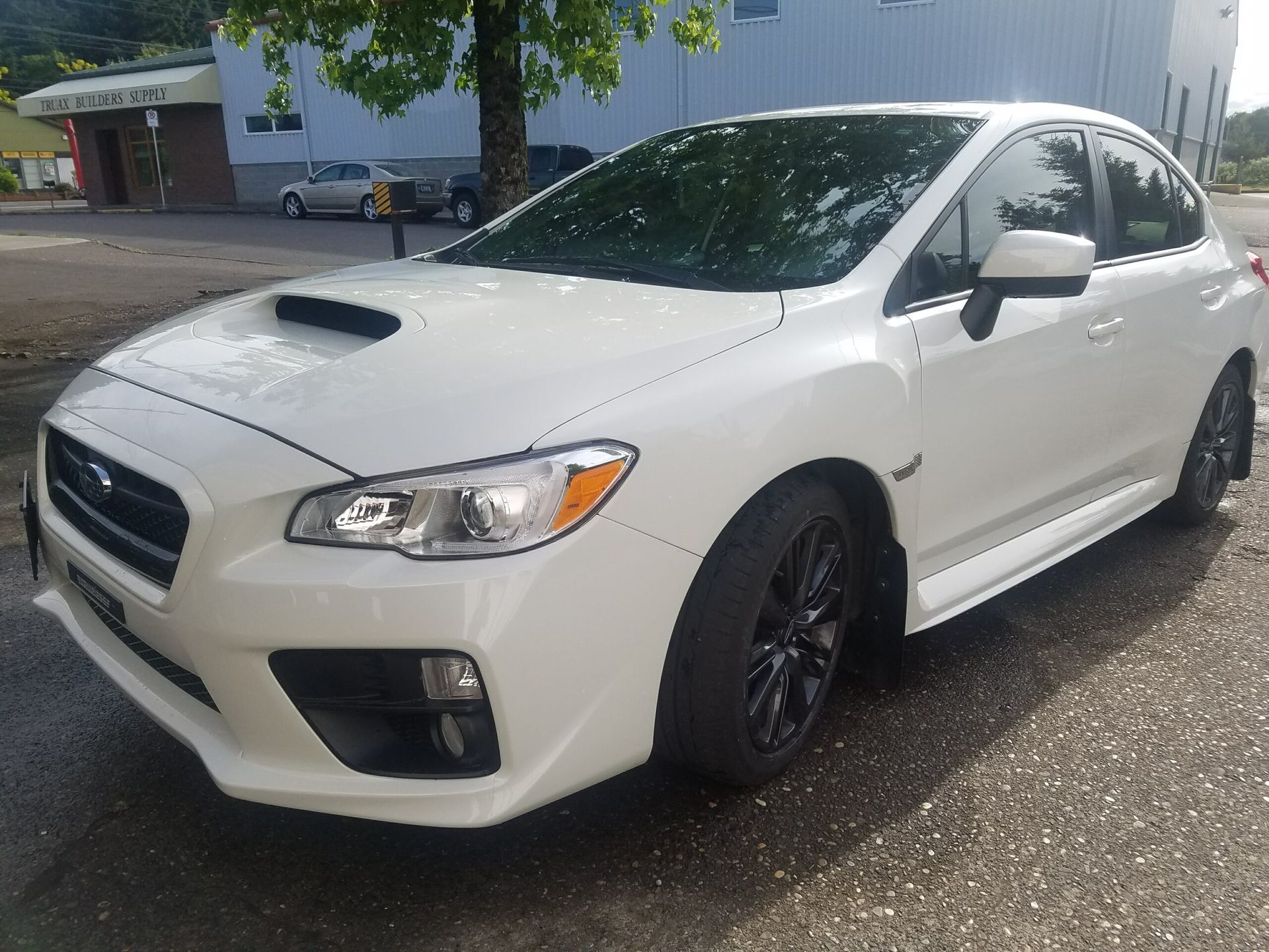 White sports sedan parked outdoors in a lot, front three-quarter view.