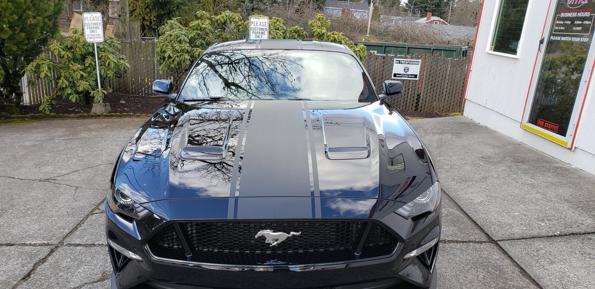 Blue sports car with black racing stripes parked in a driveway