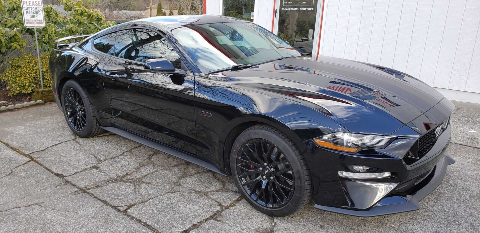 Black sports coupe parked outside a building, side view